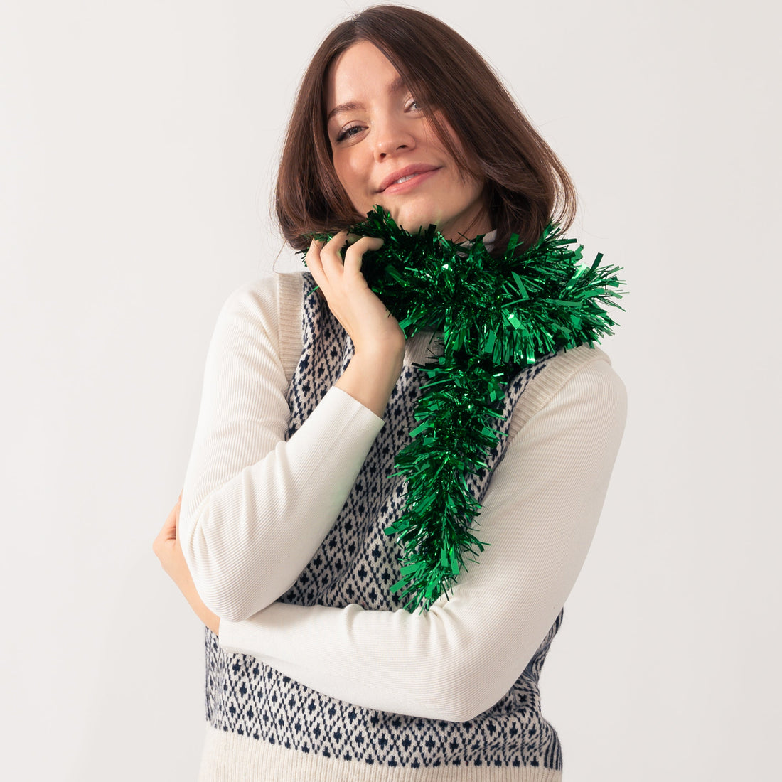 Women poses in a cosy jumper with tinsel wrapped around her neck