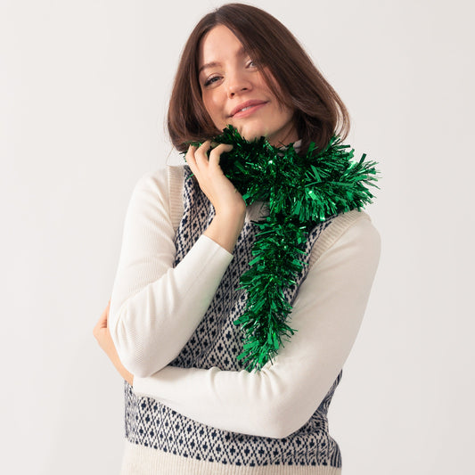 Women poses in a cosy jumper with tinsel wrapped around her neck
