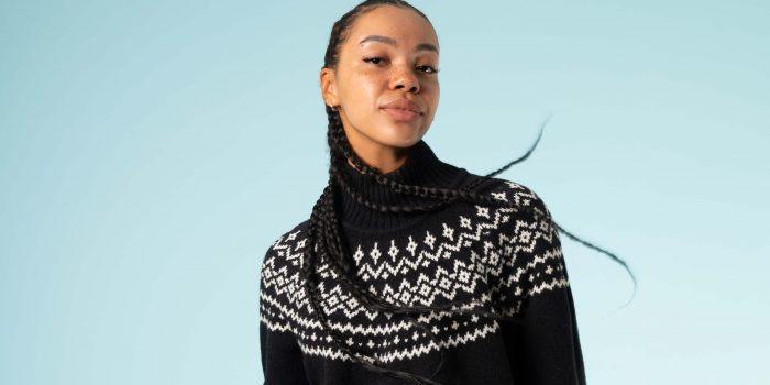 A woman of colour poses in a fairisle jumper