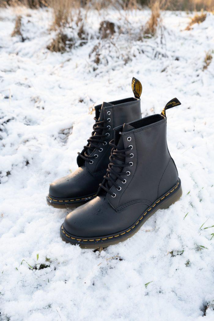 A pair of black Dr Martens boots in the snow