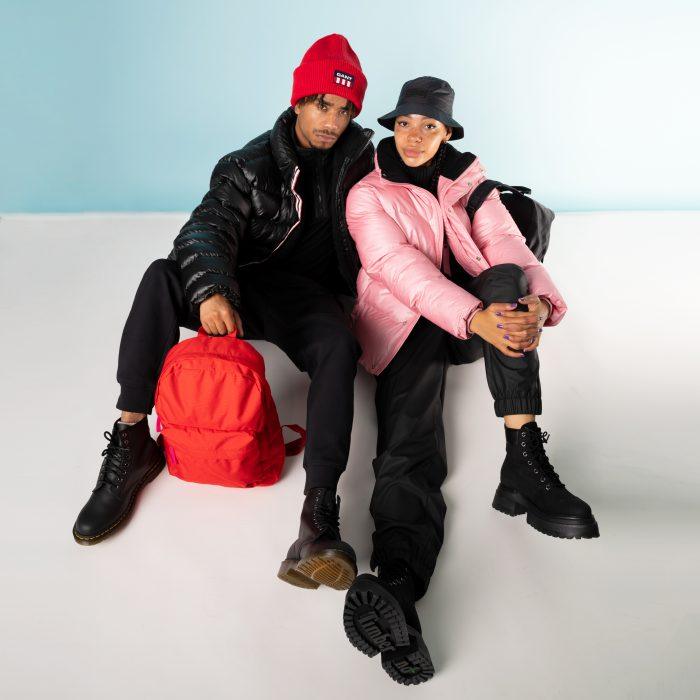 A couple wear apres ski clothes and sit cuddled together on the floor
