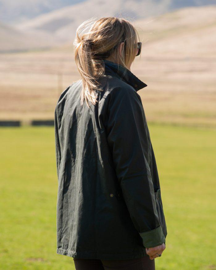 A blonde woman wears a wax barbour jacket