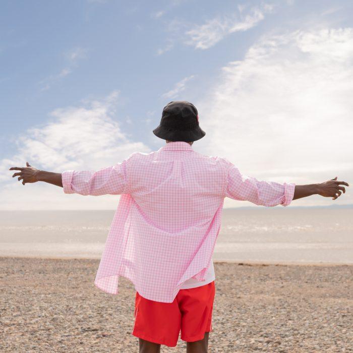 Shot from behind of a man stood on the beach holding his arms wide open
