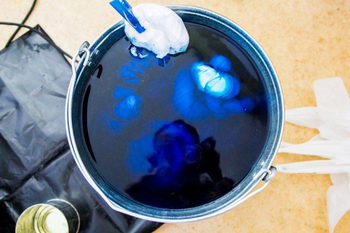 A bucket filled with die on a surface ready for hand-dyeing jeans