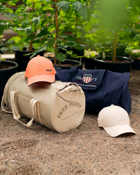 Fred Perry and Gant duffle bags on the ground in a fancy garden