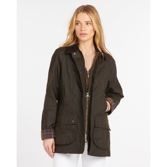 White woman with blonde hair wears an olive green classic Beadnell jacket with white jeans and an oatmeal jumper