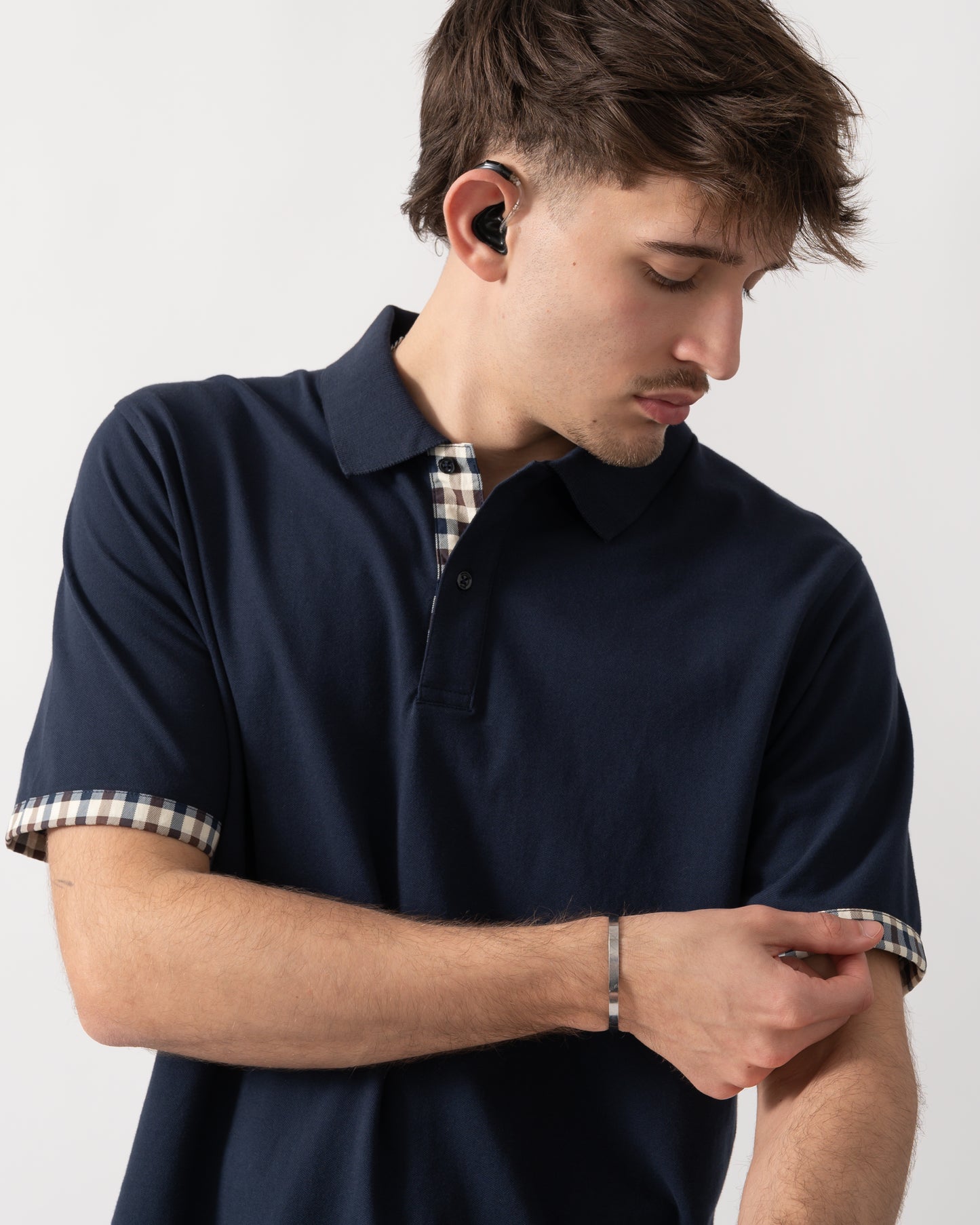 close up shot of a model wearing an Aquascutum Mens Club Check Stretch Piquet Sleeves Polo Shirt in Navy 11