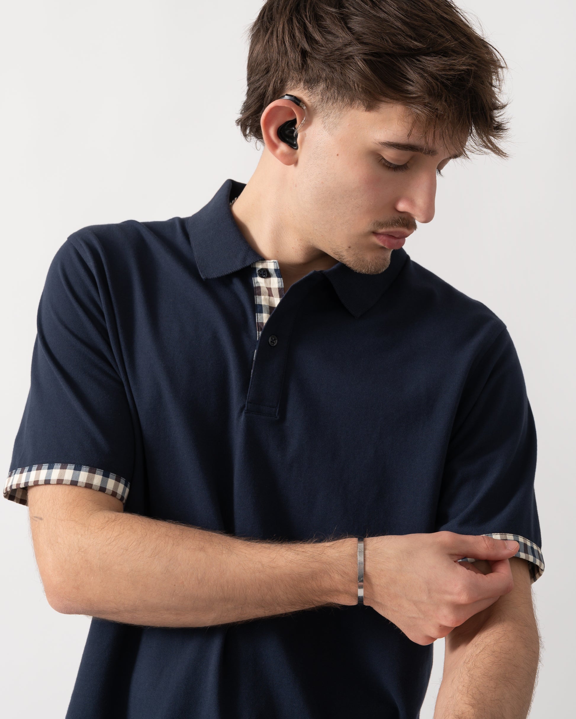 close up shot of a model wearing an Aquascutum Mens Club Check Stretch Piquet Sleeves Polo Shirt in Navy 11