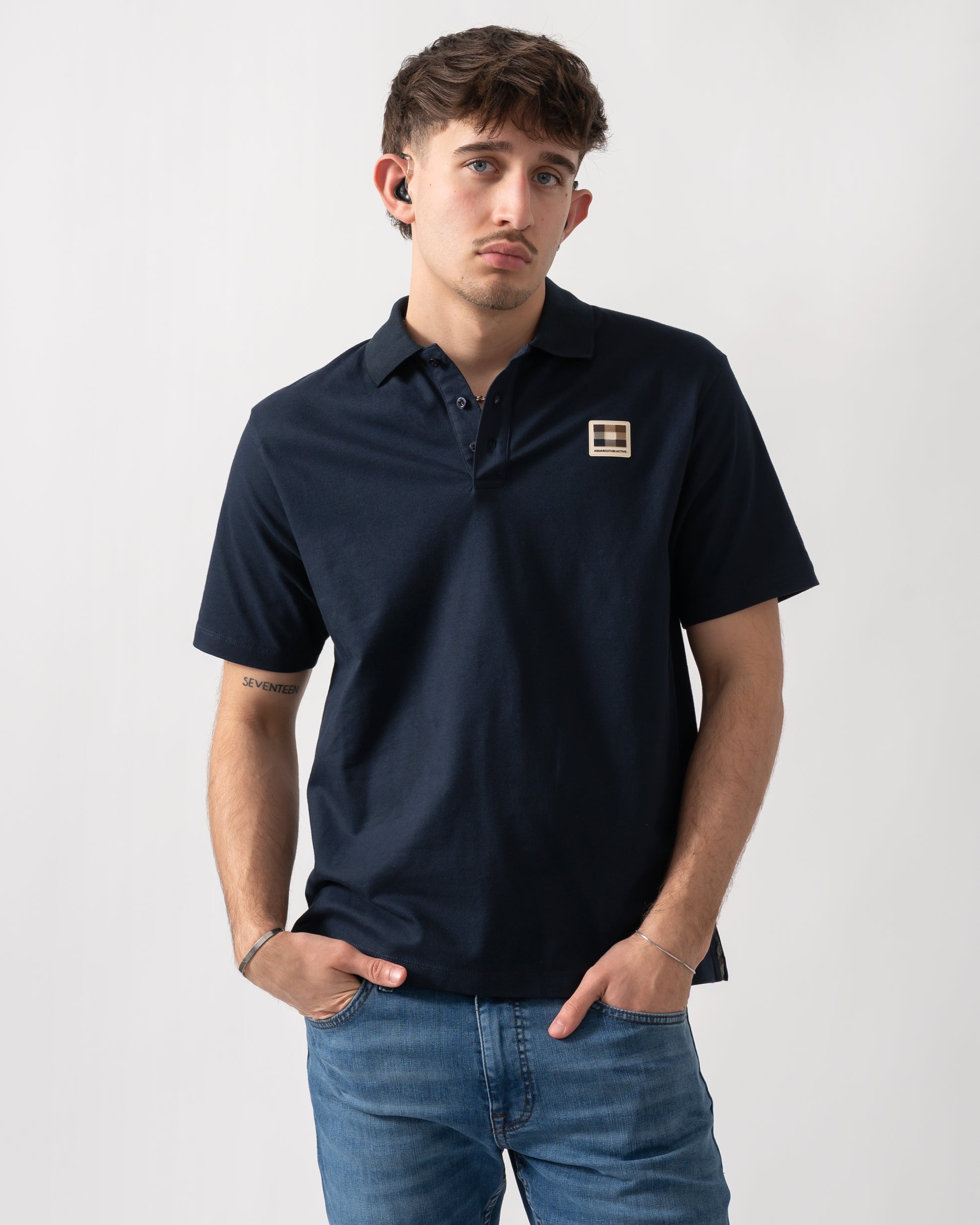 Studio shot of a model wearing an Aquascutum Mens Stretch Piquet Badge Polo Shirt in Navy 11
