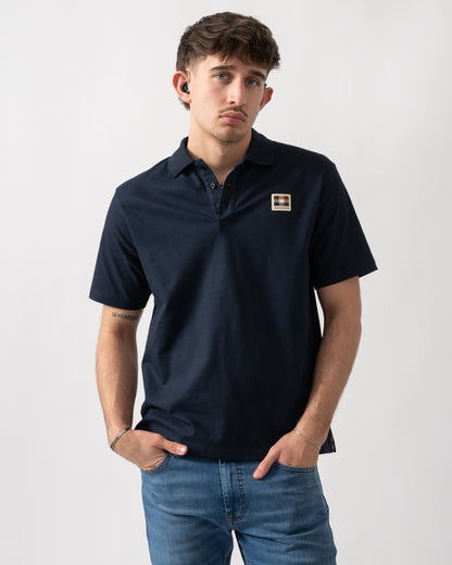 Studio shot of a model wearing an Aquascutum Mens Stretch Piquet Badge Polo Shirt in Navy 11