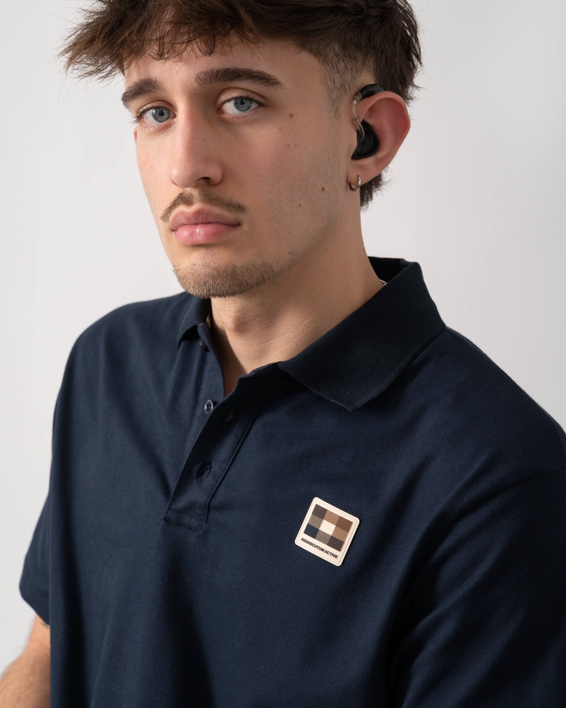 close up shot of a model wearing an Aquascutum Mens Stretch Piquet Badge Polo Shirt in Navy 11