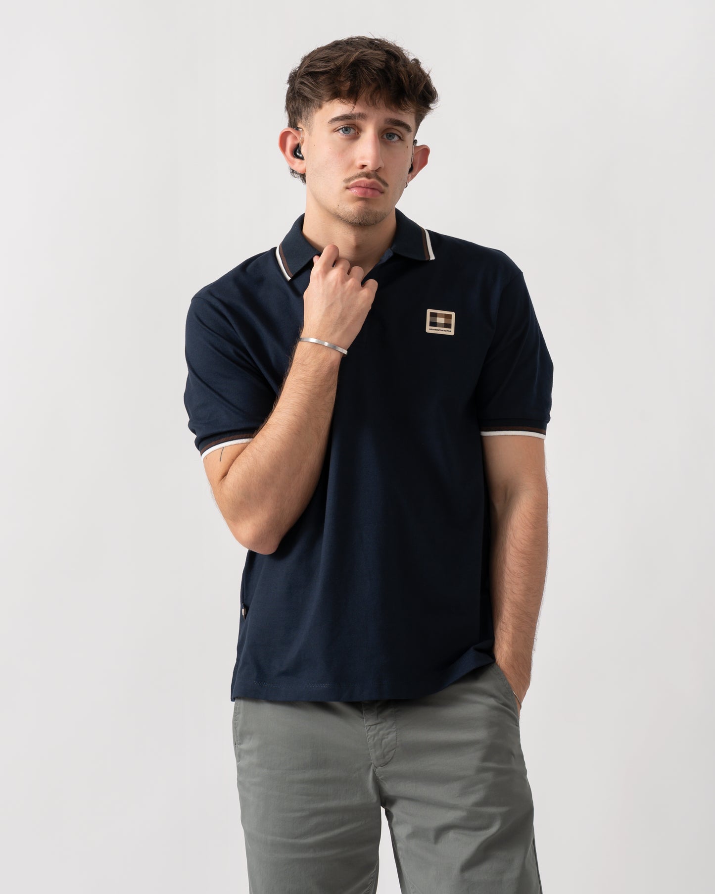 studio shot of a model wearing an Aquascutum Mens Stretch Piquet Tipped Badge Polo Shirt in Navy 11