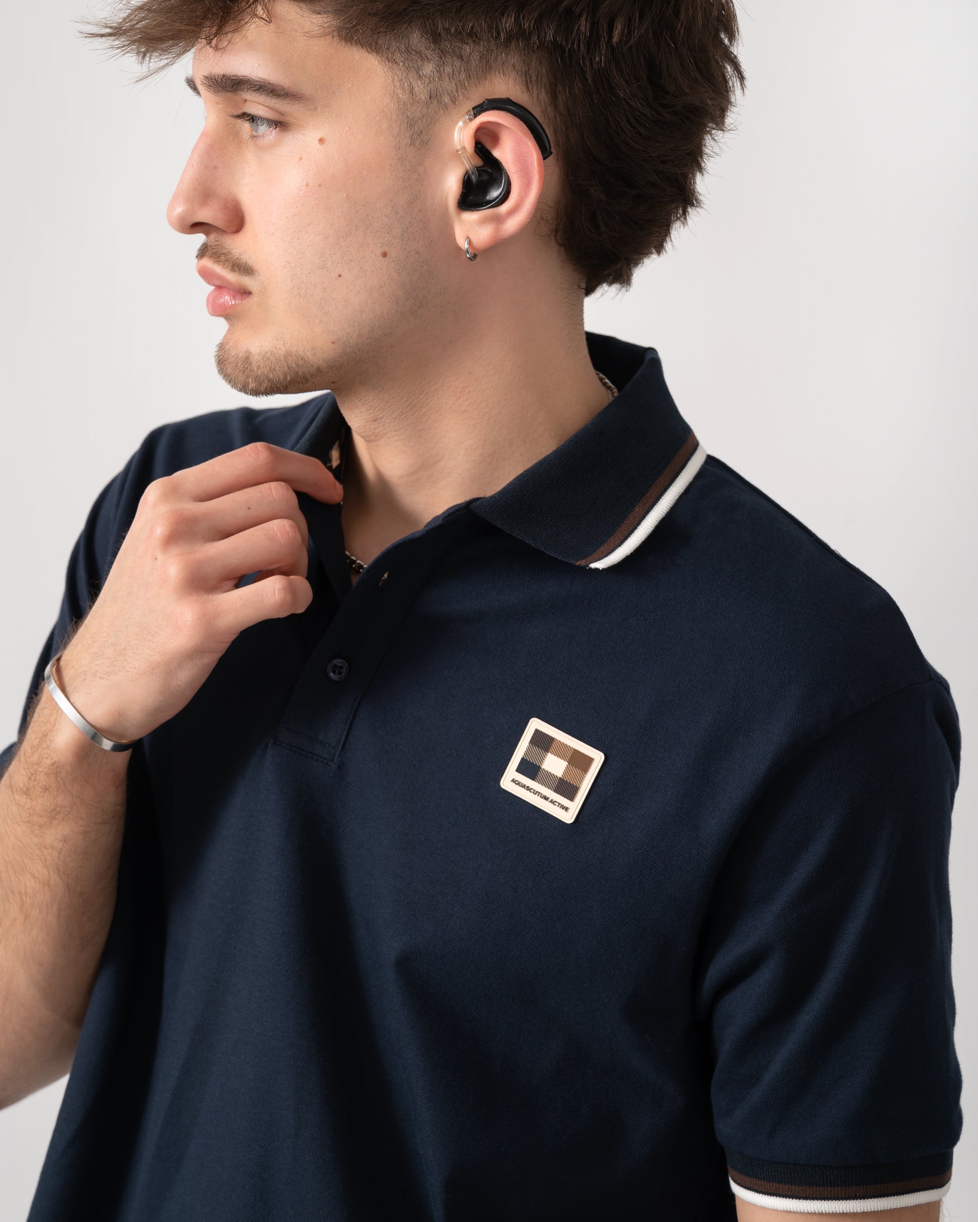 close up shot of a model wearing an Aquascutum Mens Stretch Piquet Tipped Badge Polo Shirt in Navy 11