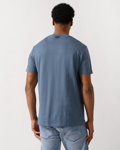 back shot of a model wearing a Armani Exchange Mens T-Shirt with Small Milano-New York Logo in China Blue