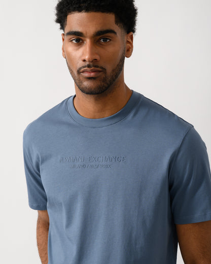 detail view of a Model wearing an Armani Exchange Mens T-Shirt with Tonal Milano/New York Logo in China Blue U9302