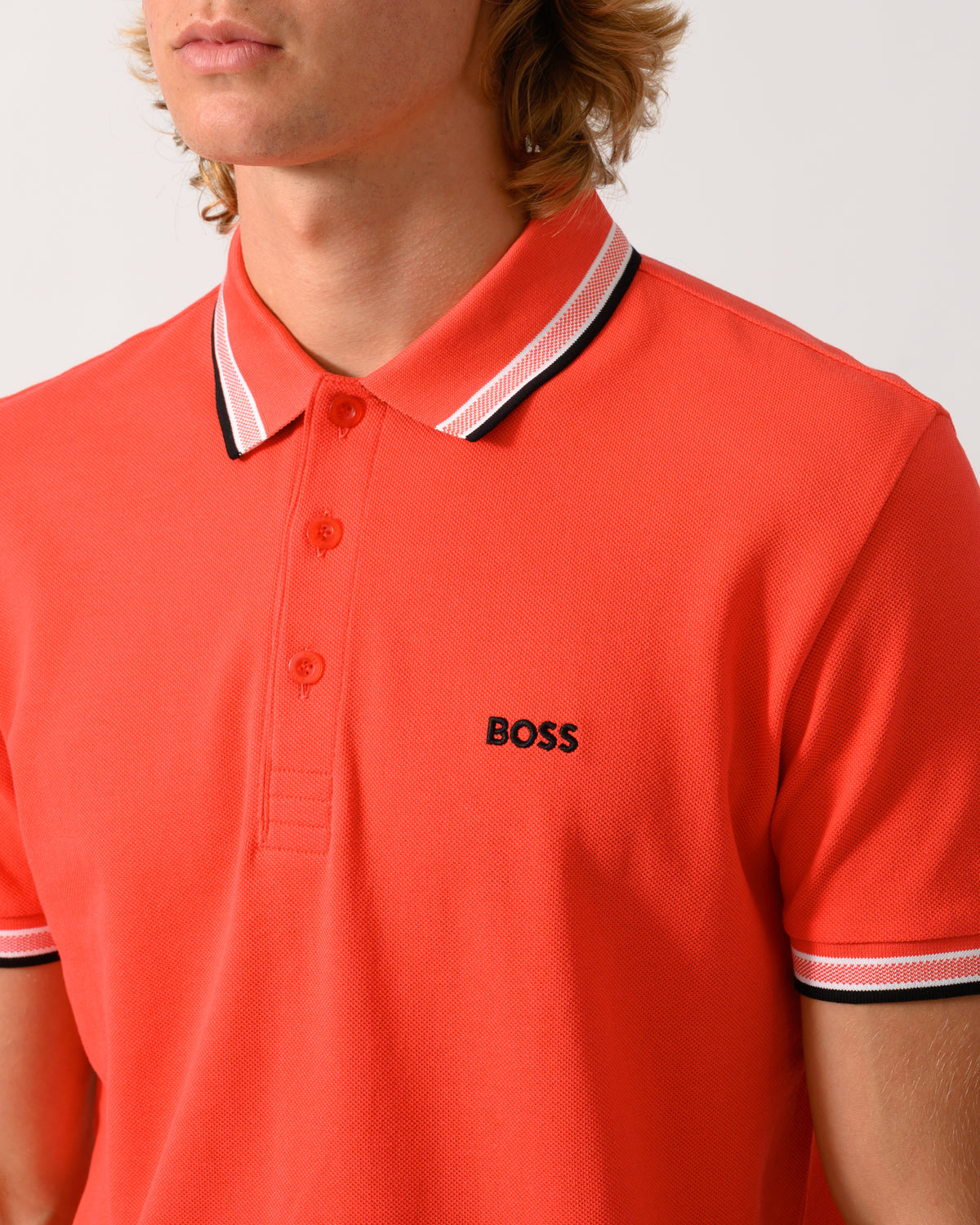close up studio photograph of a model wearing a BOSS Green Paddy Mens Cotton-Piqué Polo Shirt with Contrast Logo in Bright Red 620