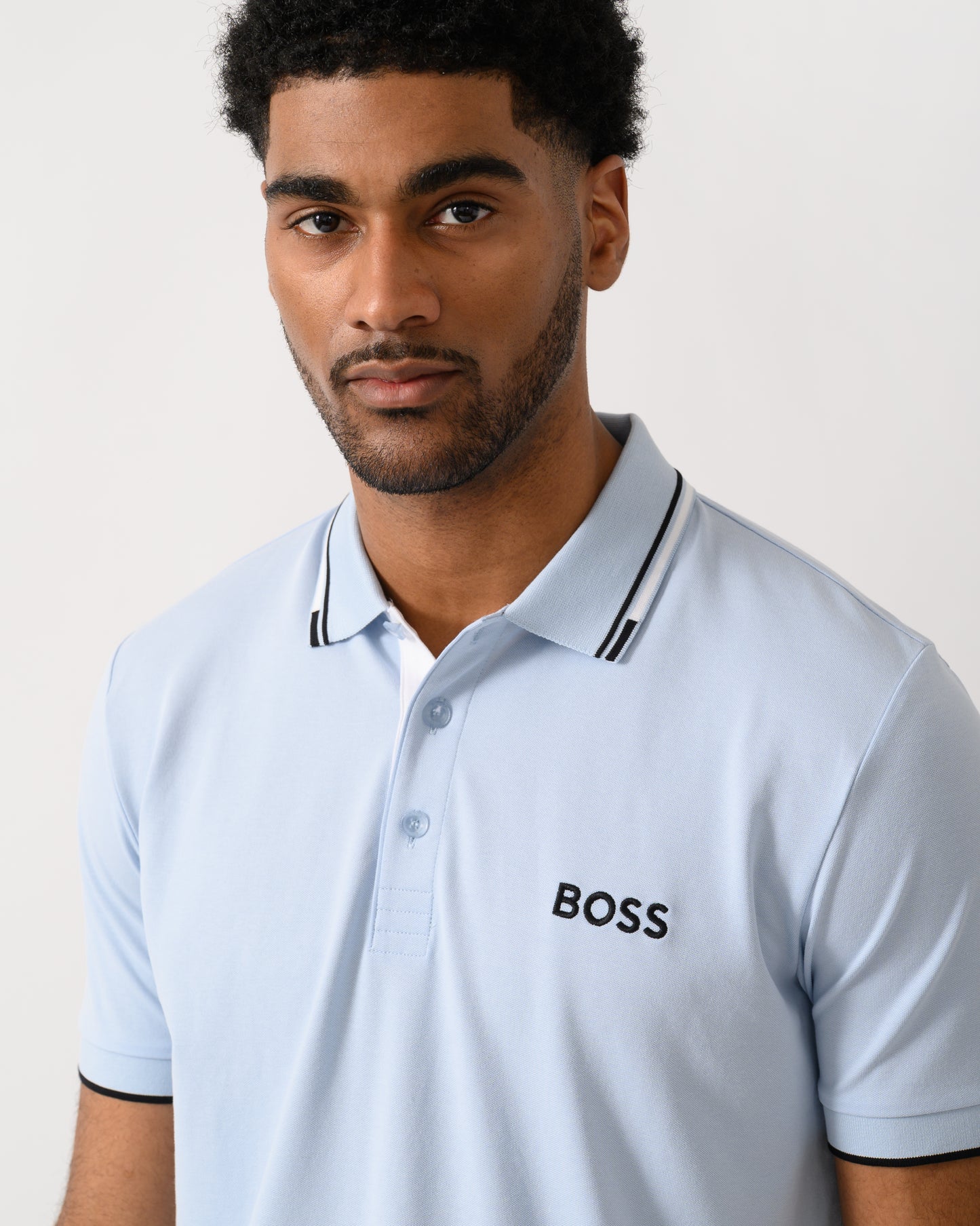 detail shot of a model wearing a BOSS Green Paddy Pro Mens Cotton Blend Polo Shirt With Contrast Logos in Open Blue 460