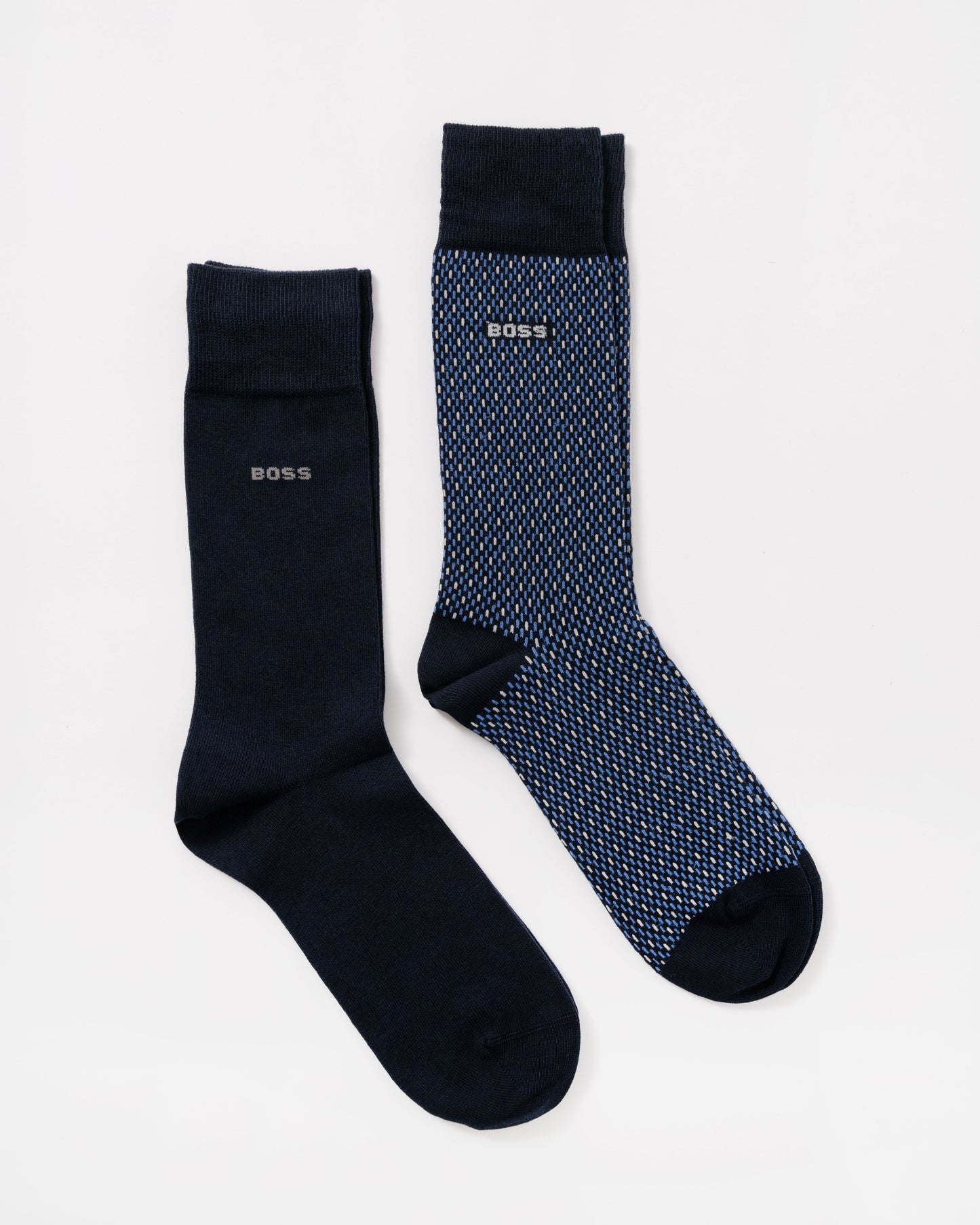 Two BOSS crew socks on a light gray background: one solid dark navy sock and one blue sock with a fine white geometric pattern.
