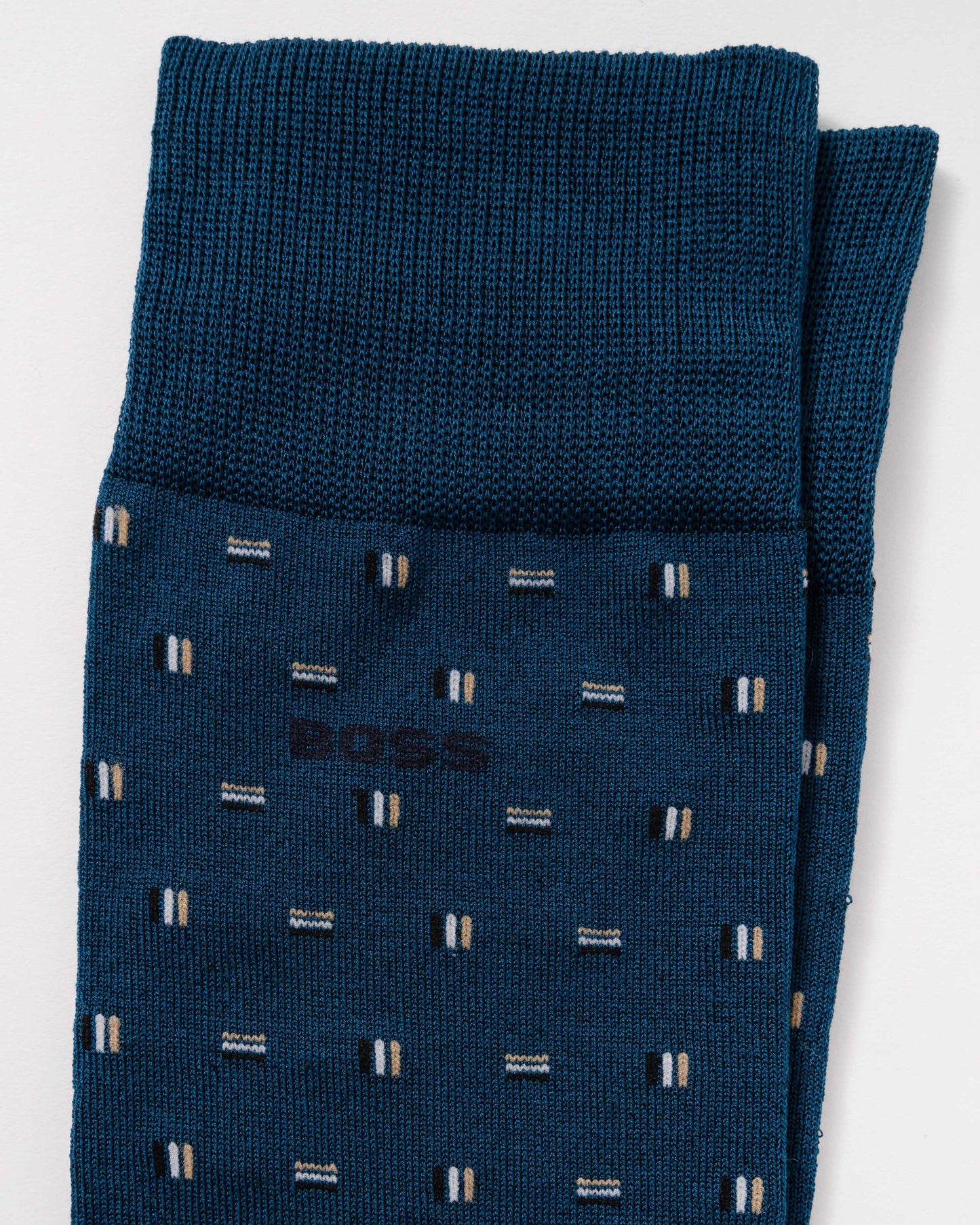 A pair of folded dark teal blue BOSS knit socks with a small geometric pattern of white and beige stripes, shown on a clean white background.