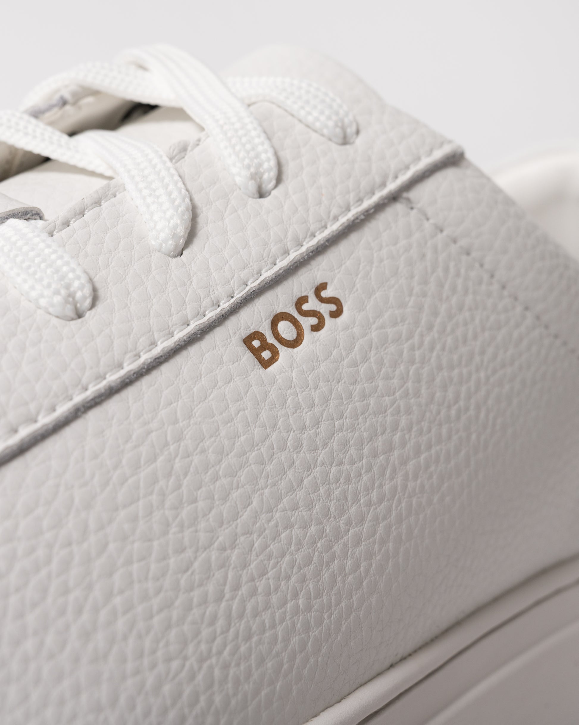 close up studio shot of BOSS Orange Kieran Mens Grained-leather trainers with rubber sole in White 100