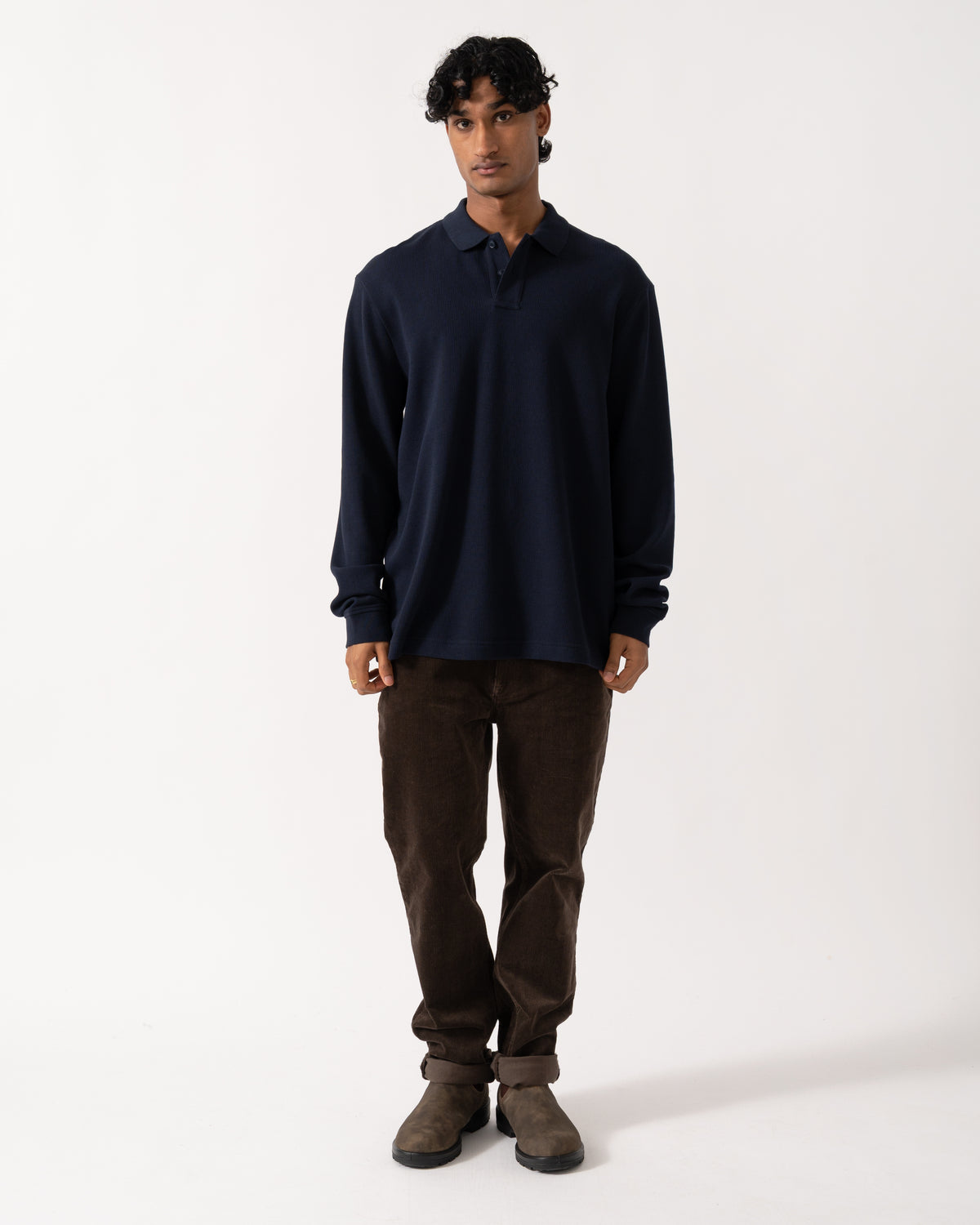 full length studio photograph showing a model wearing a BOSS Orange Petempestolong Mens Long Sleeve Polo Shirt in Dark Blue 404
