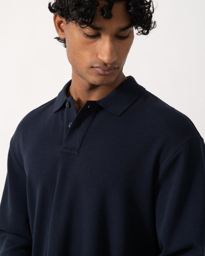 close up studio photograph showing a model wearing a BOSS Orange Petempestolong Mens Long Sleeve Polo Shirt in Dark Blue 404