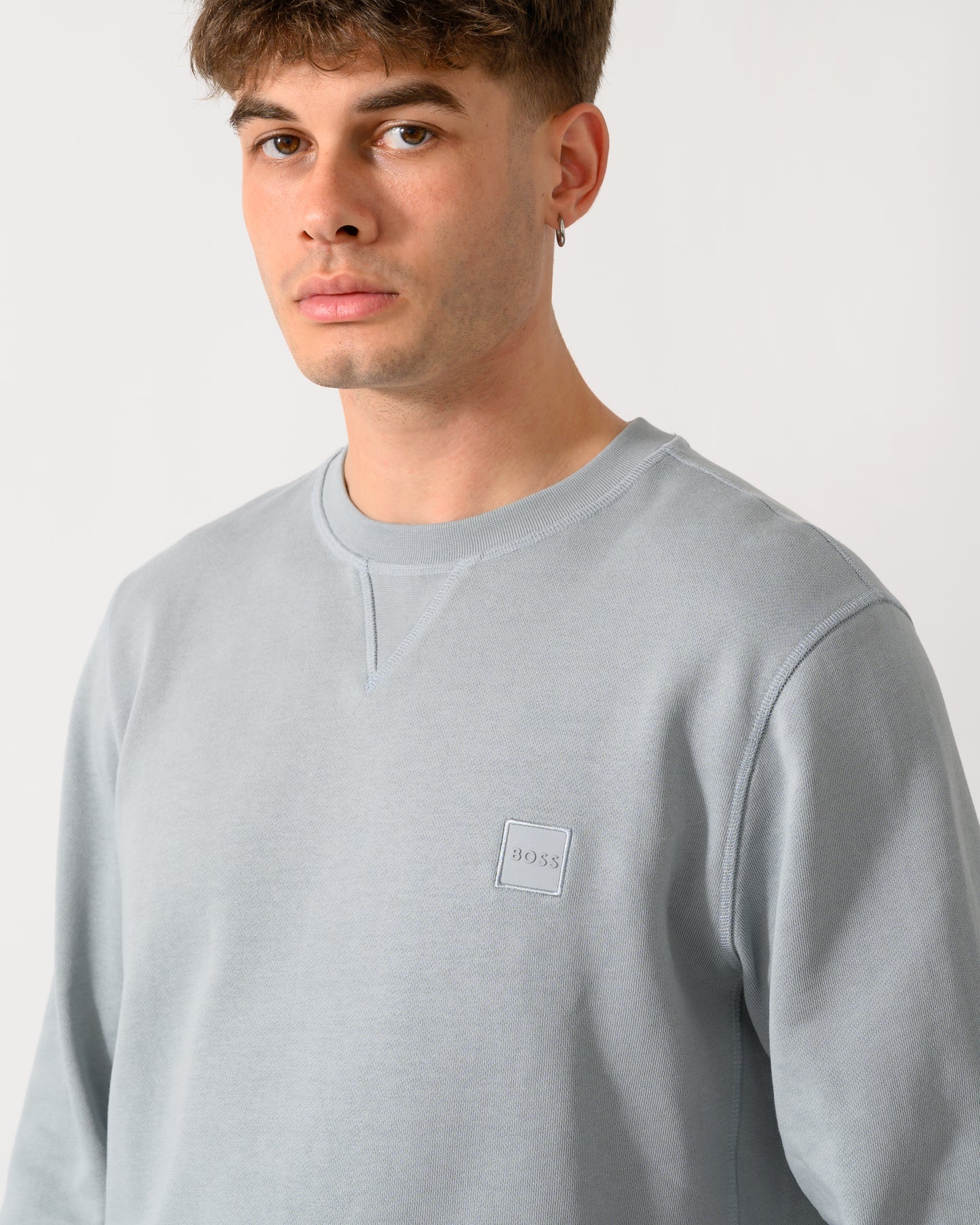 close up shot of a model wearing a BOSS Orange Westart Mens Crew Neck Sweatshirt With Logo Patch in Open Grey 084