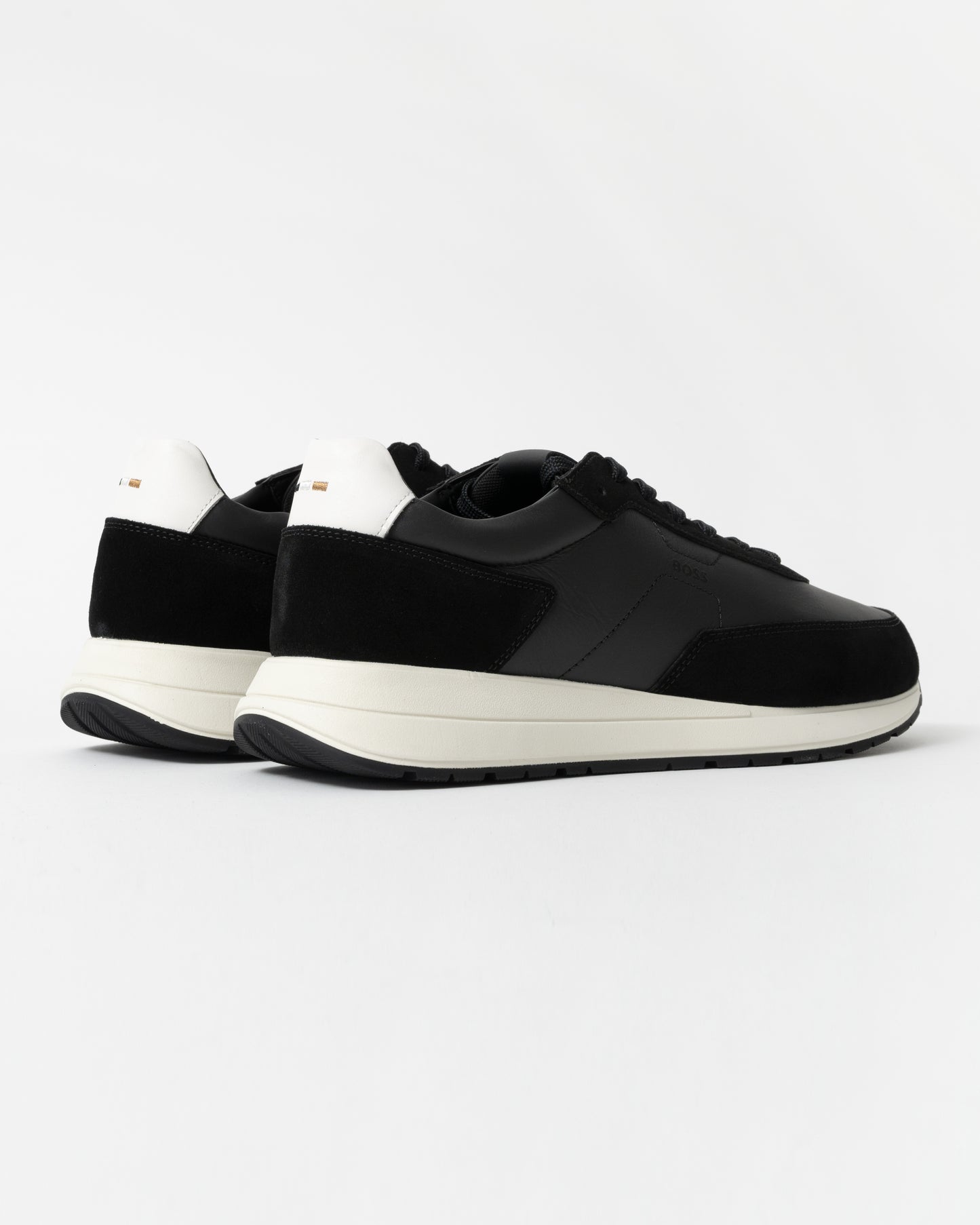 Black sneakers with white soles on a light gray background