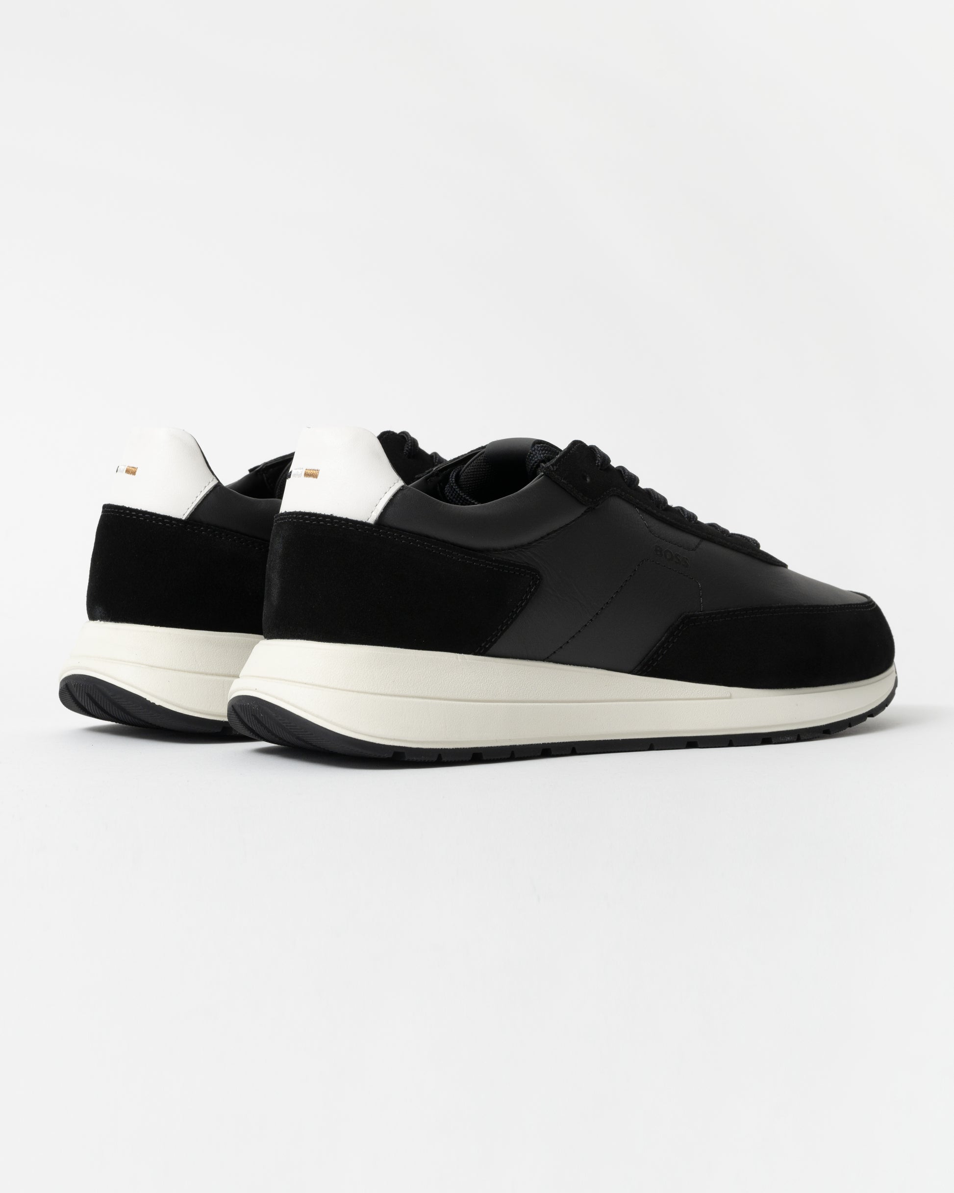 Black sneakers with white soles on a light gray background