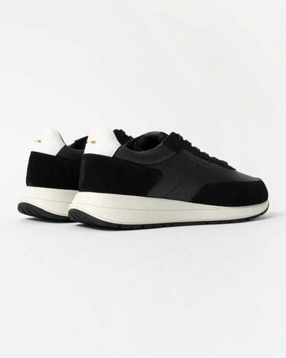 Black sneakers with white soles on a light gray background