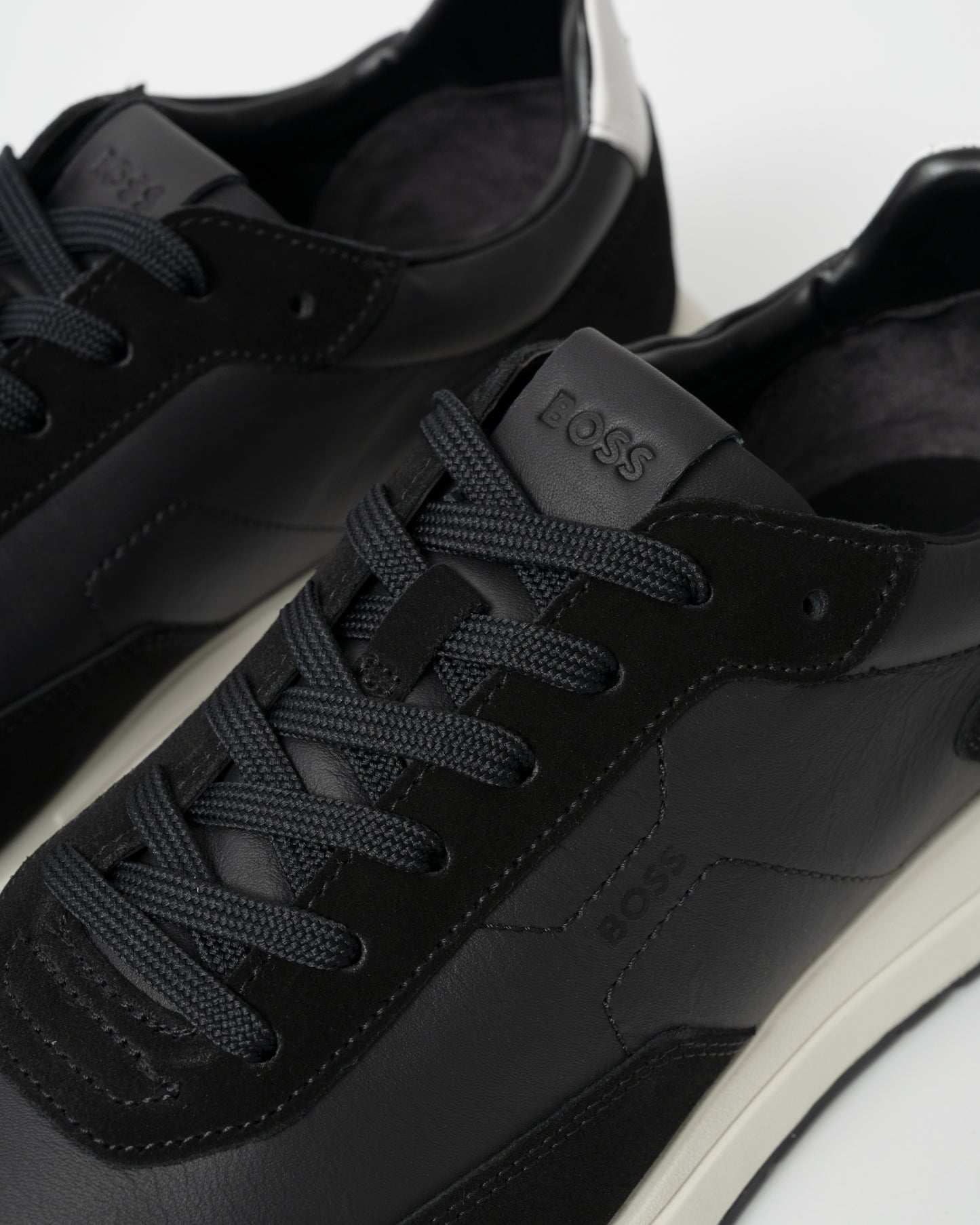 Black sneakers with 'BOSS' branding on a white background