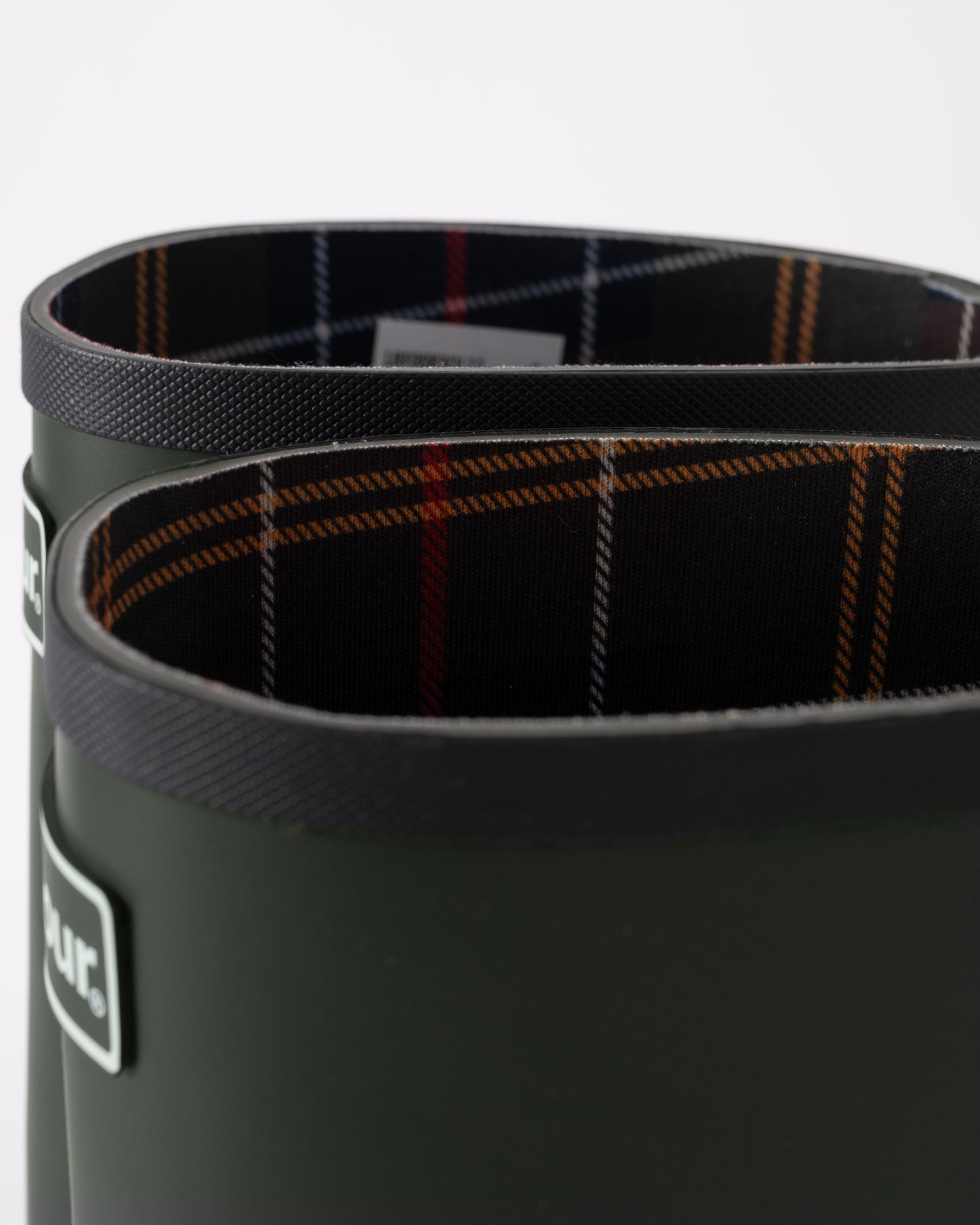 Close-up of a green wellington boot with plaid lining on a white background