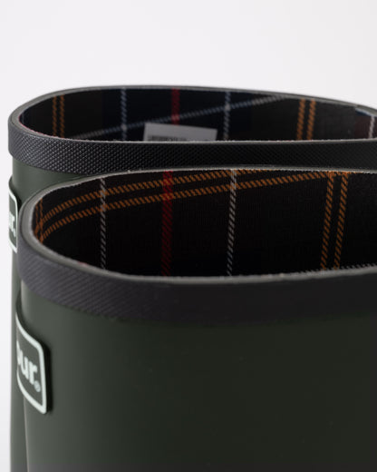 Close-up of a green wellington boot with plaid lining on a white background