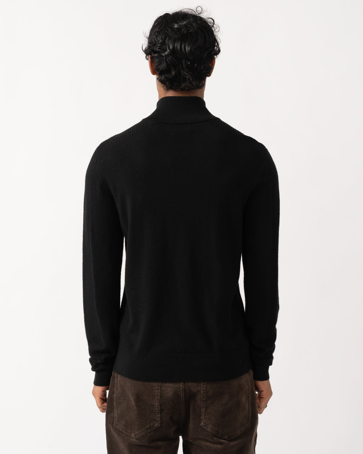 Studio photograph showing the back of a model wearing a Belstaff Mens Colden Merino Quarter Zip Jumper in Black