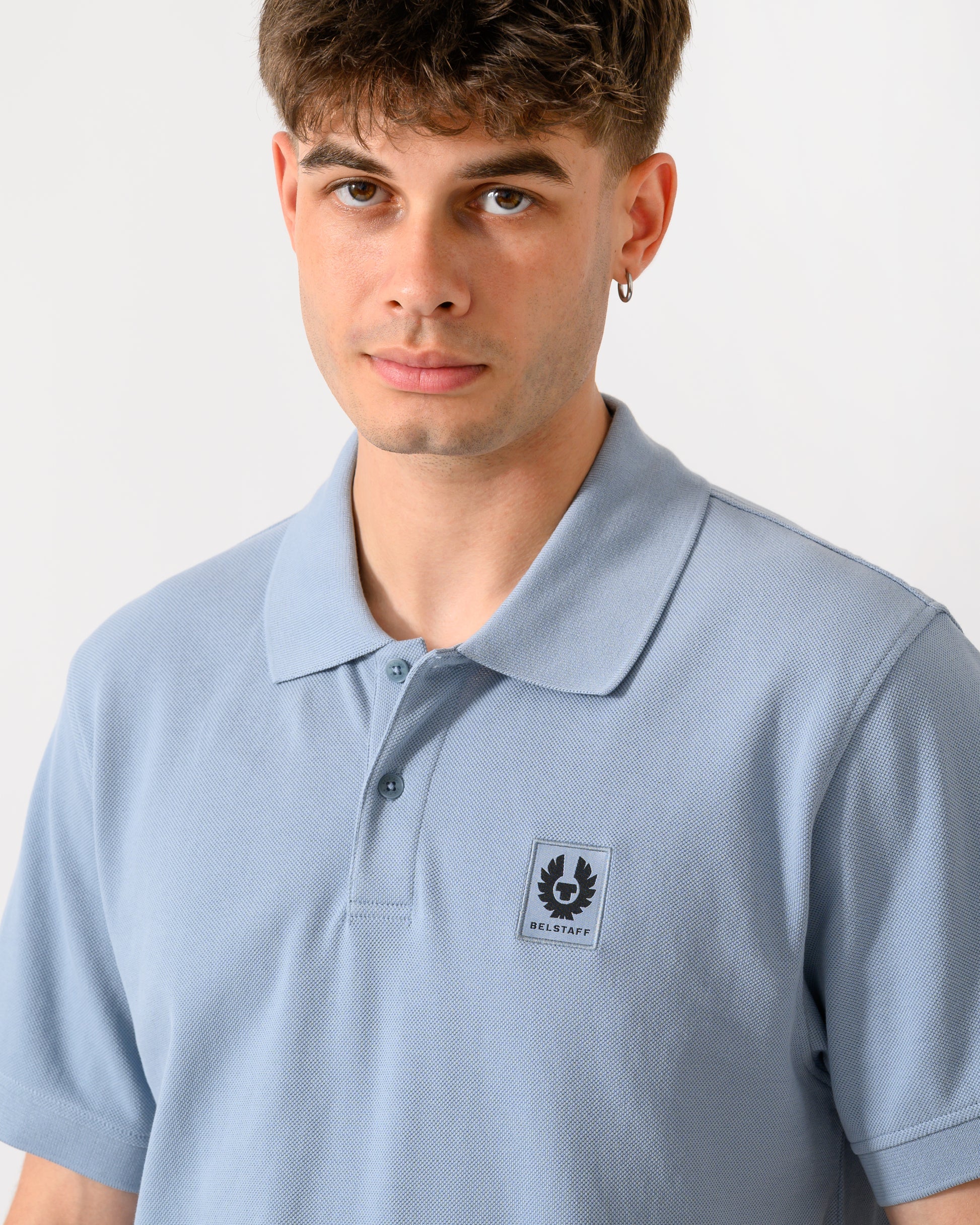 close up of a model wearing a Belstaff Mens Logo Polo in Mist Blue