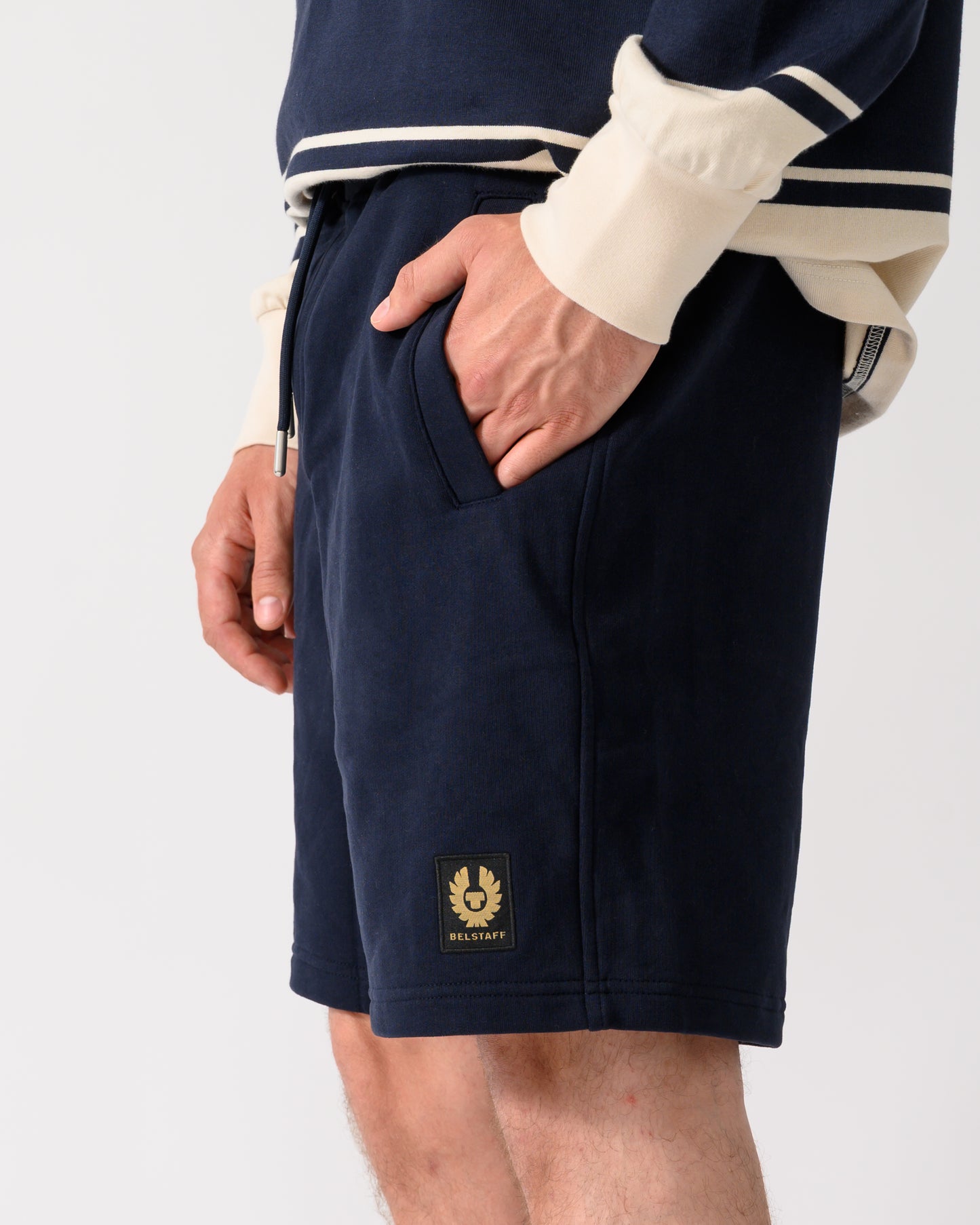 side shot of model wearing a pair of Belstaff Mens Logo Sweatshorts in Dark Ink