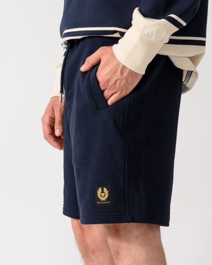 side shot of model wearing a pair of Belstaff Mens Logo Sweatshorts in Dark Ink