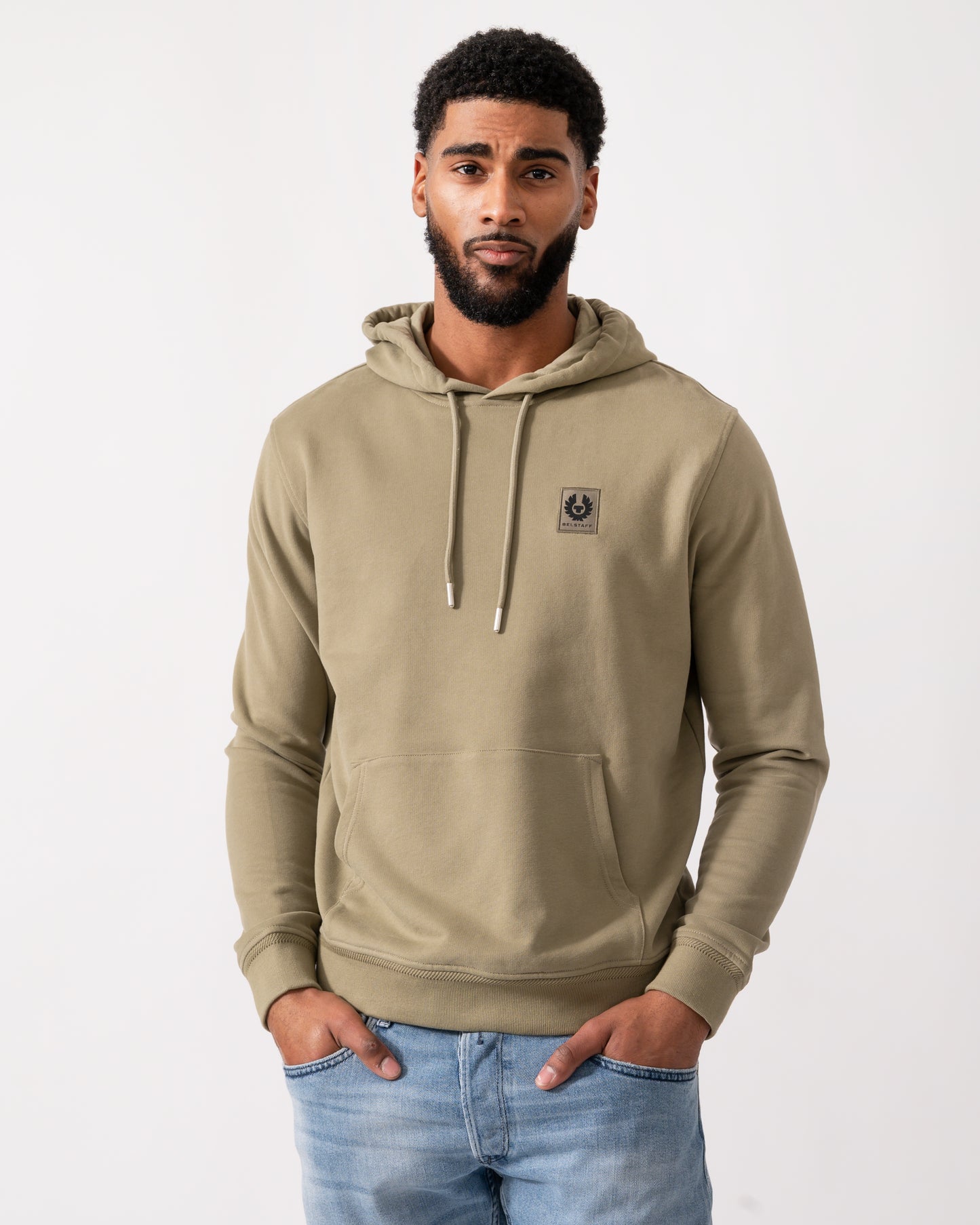 Model wearing a Belstaff Mens Pullover Logo Patch Hoodie in Fatigue Green
