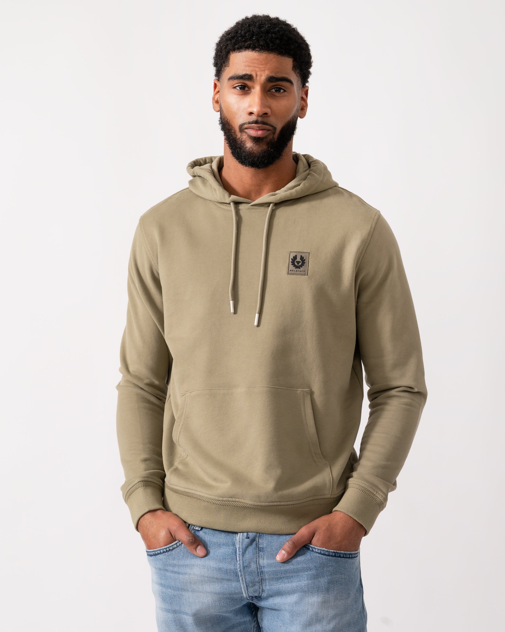 Model wearing a Belstaff Mens Pullover Logo Patch Hoodie in Fatigue Green