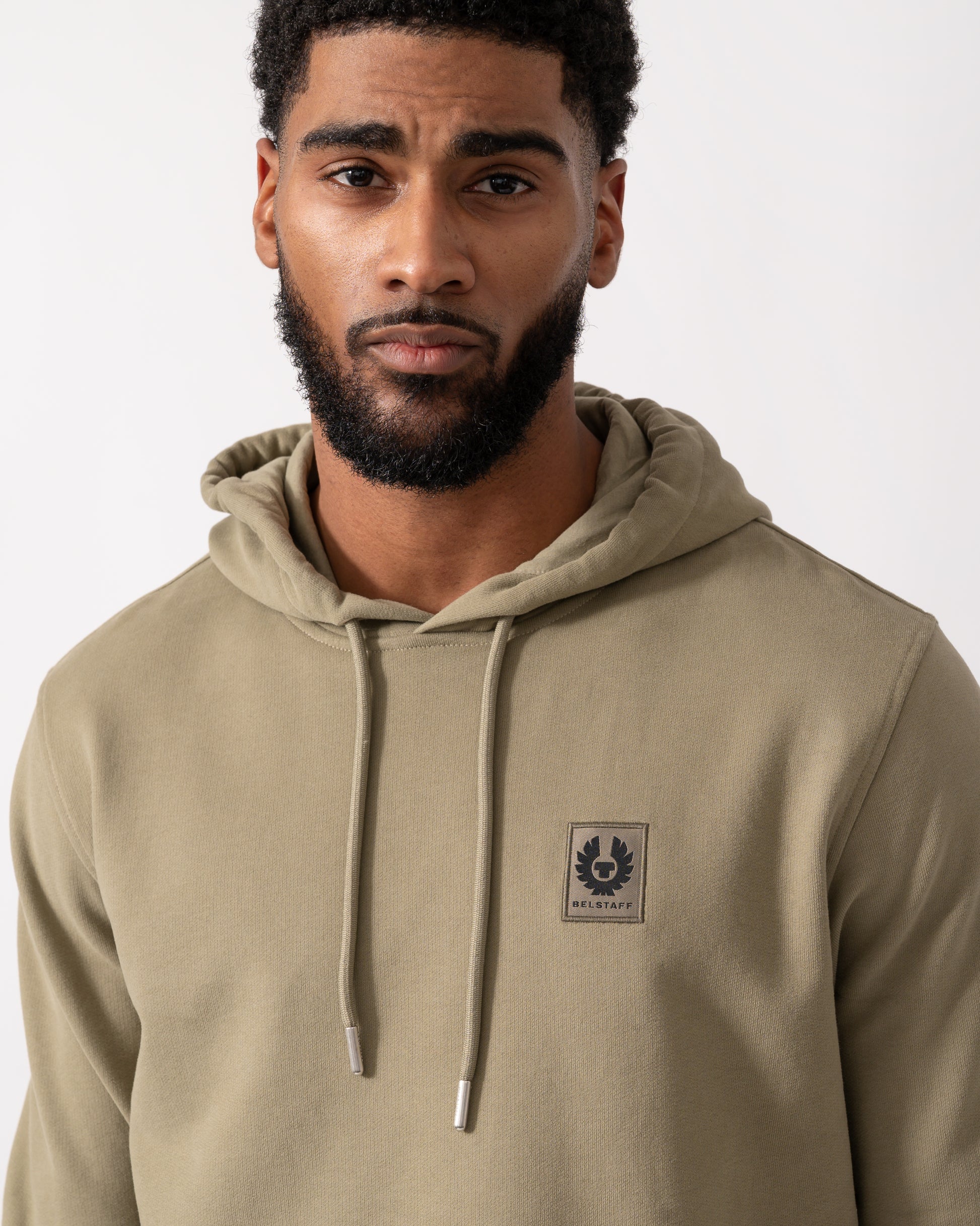 close up of a Model wearing a Belstaff Mens Pullover Logo Patch Hoodie in Fatigue Green