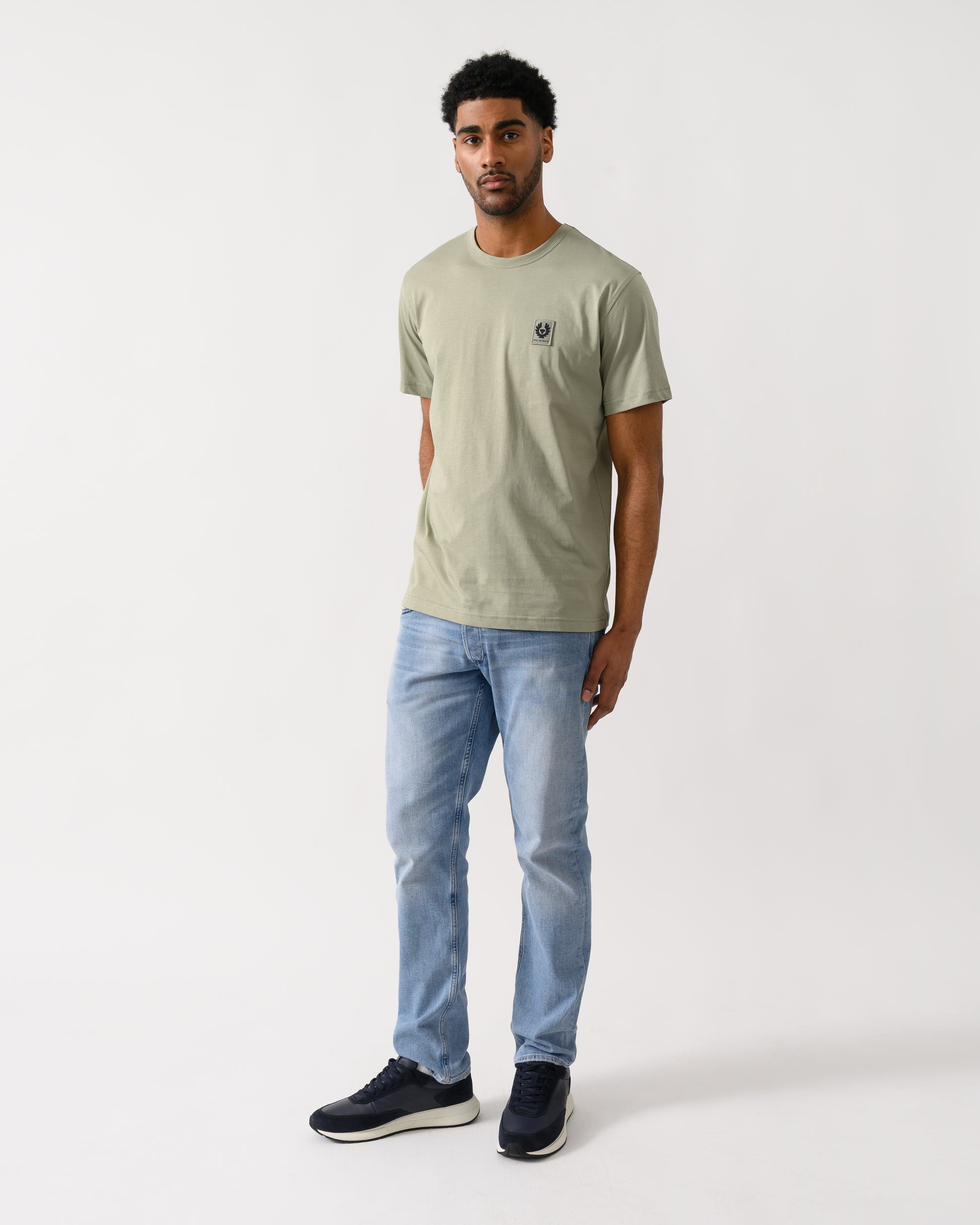 full length view of a Model wearing a Belstaff Short Sleeved Mens Logo Patch T-Shirt in Lichen colour