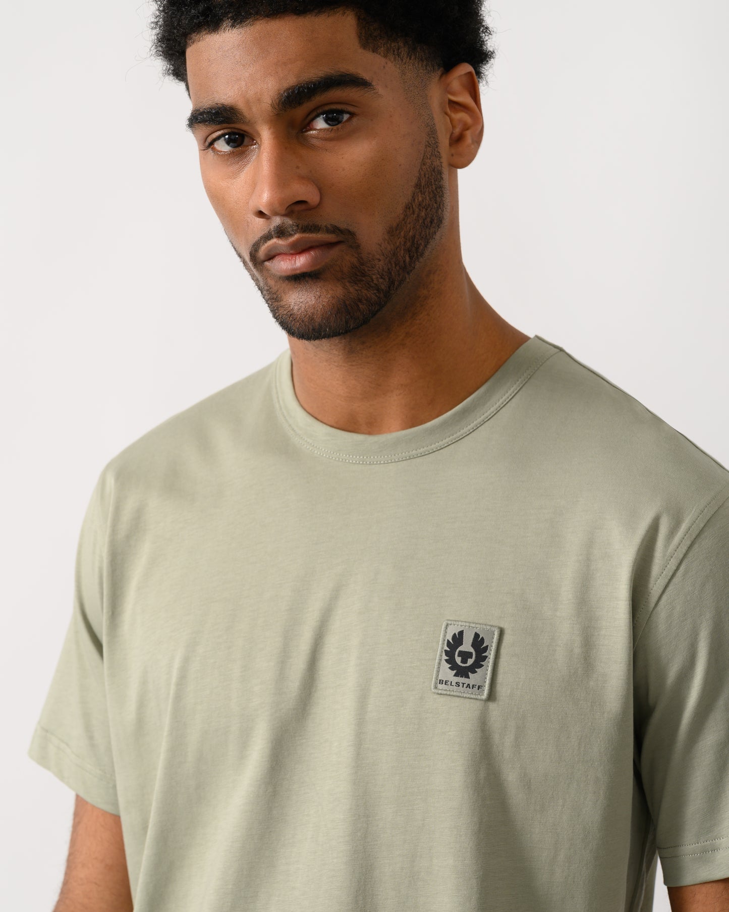 detail view of a Model wearing a Belstaff Short Sleeved Mens Logo Patch T-Shirt in Lichen colour