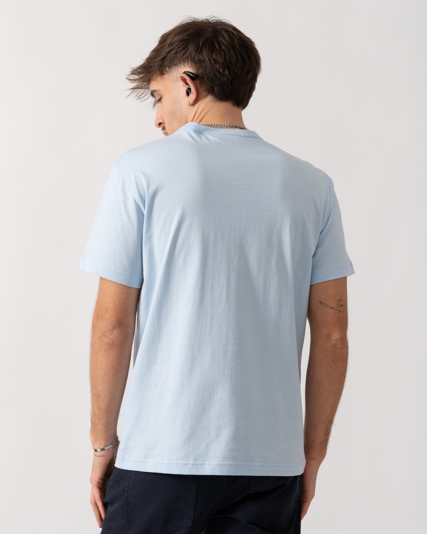 Person wearing a light blue t-shirt on a plain background