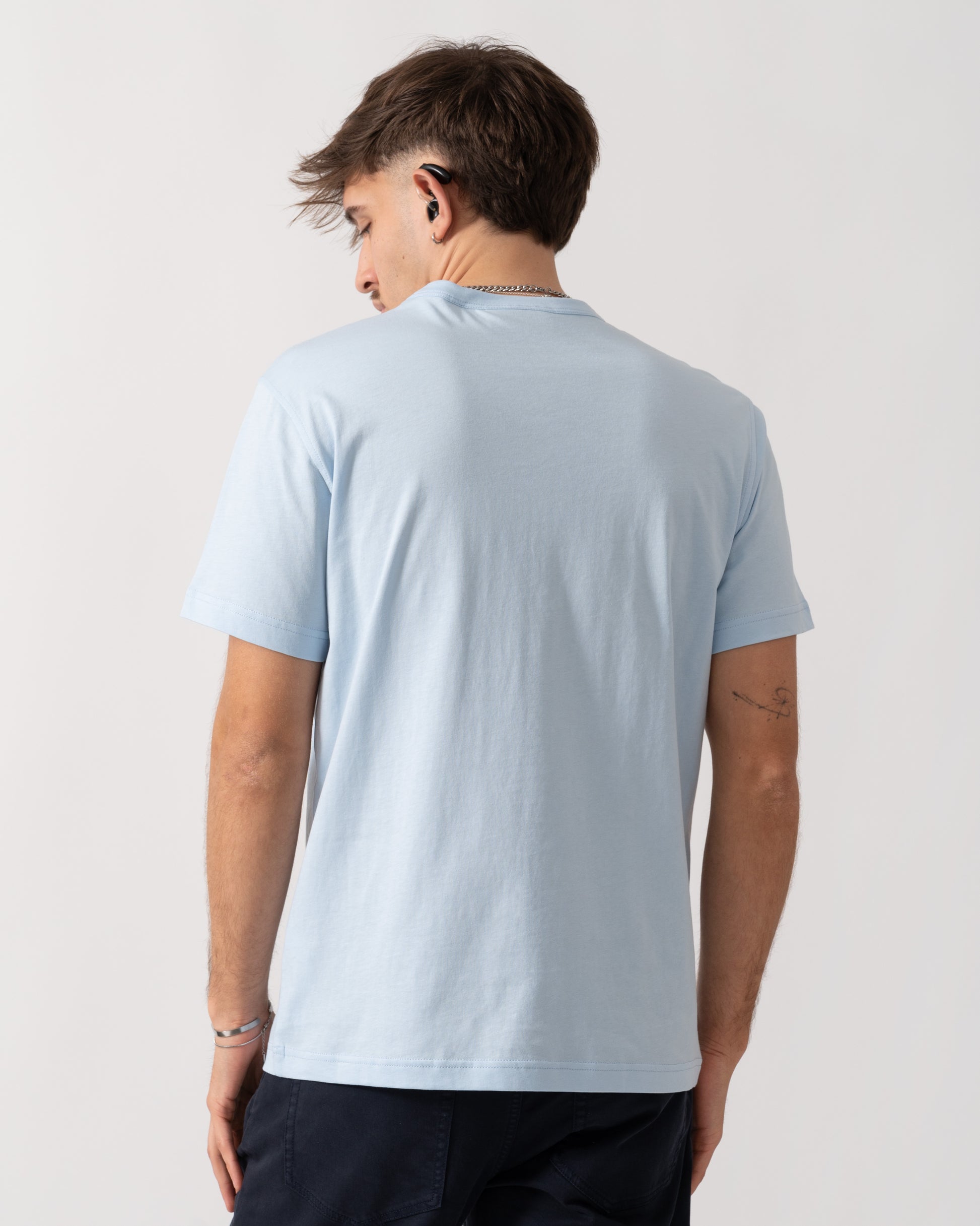 Person wearing a light blue t-shirt on a plain background