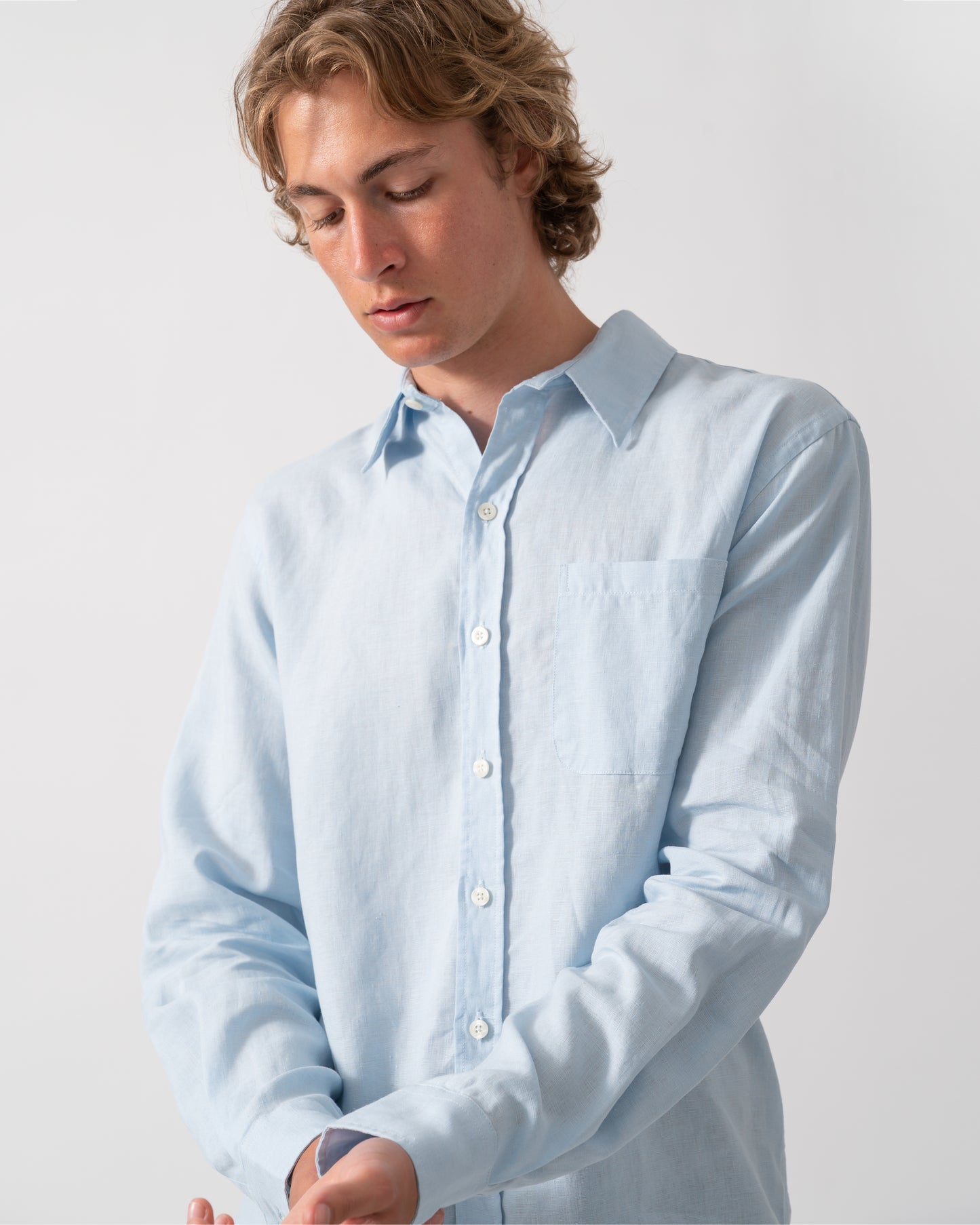 close up shot of a Model wearing a Colorful Standard Mens Long Sleeve Linen Shirt in Polar Blue