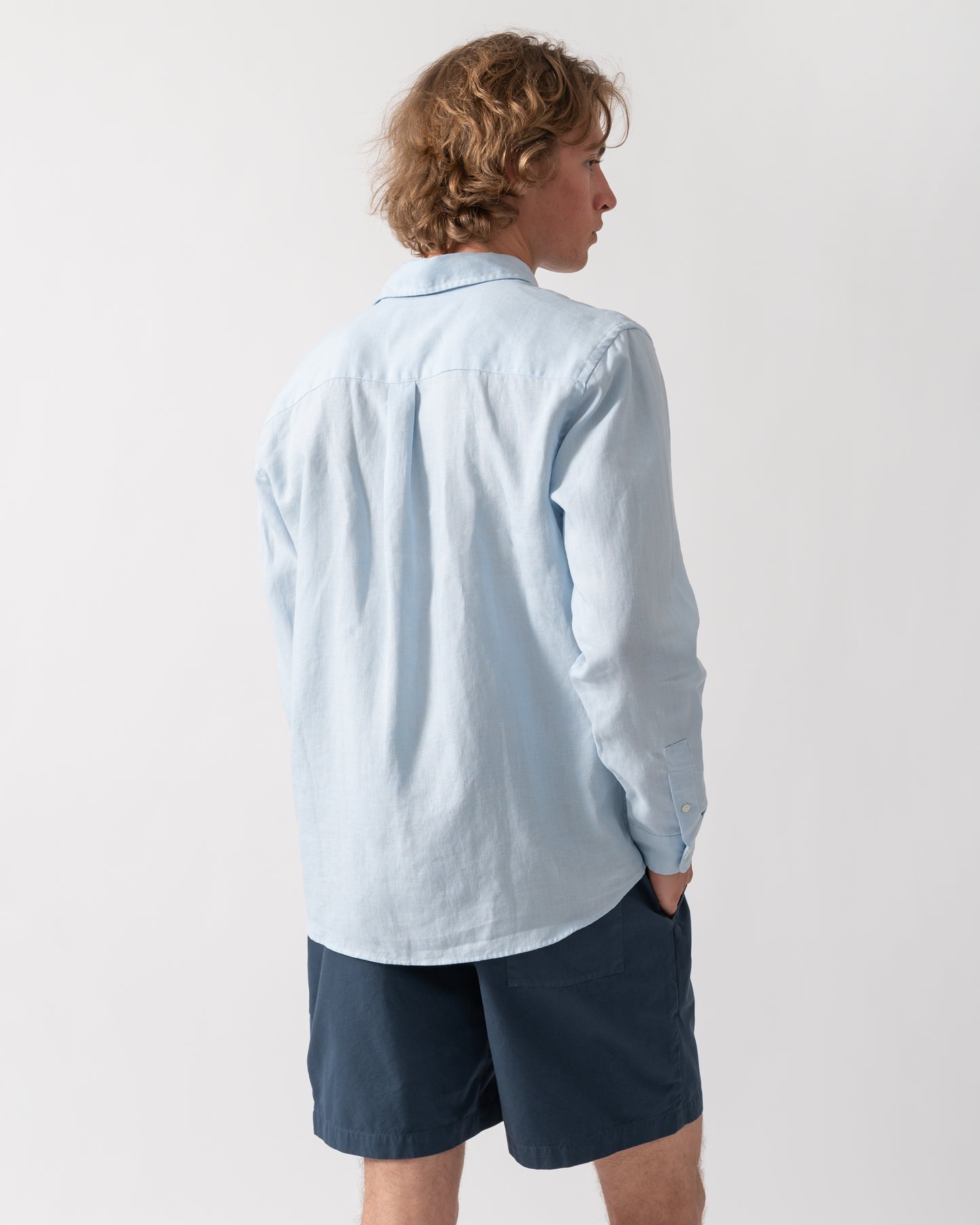back shot of a Model wearing a Colorful Standard Mens Long Sleeve Linen Shirt in Polar Blue