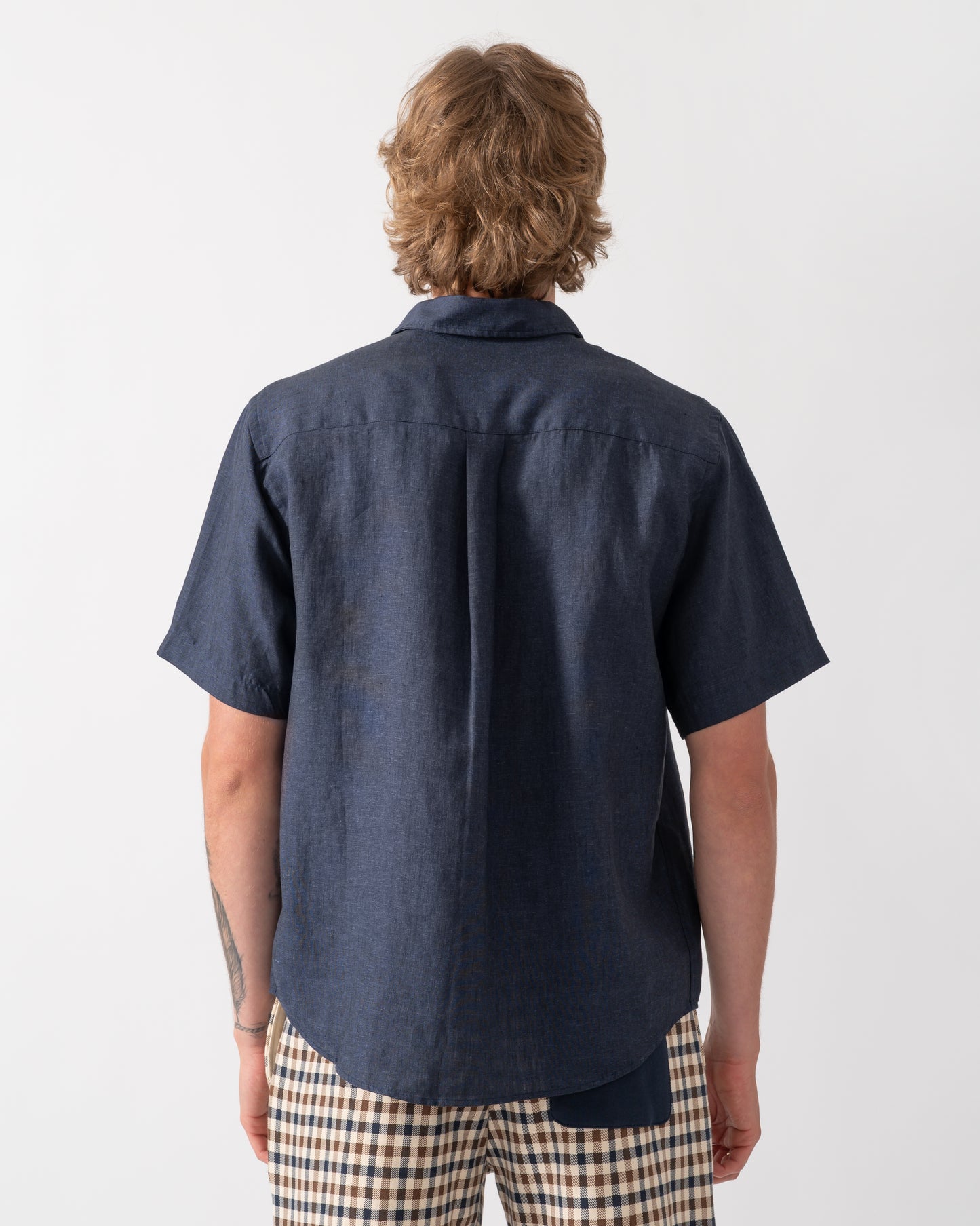 back shot of a model wearing a Colorful Standard Mens Short Sleeve Linen Shirt in Navy Blue