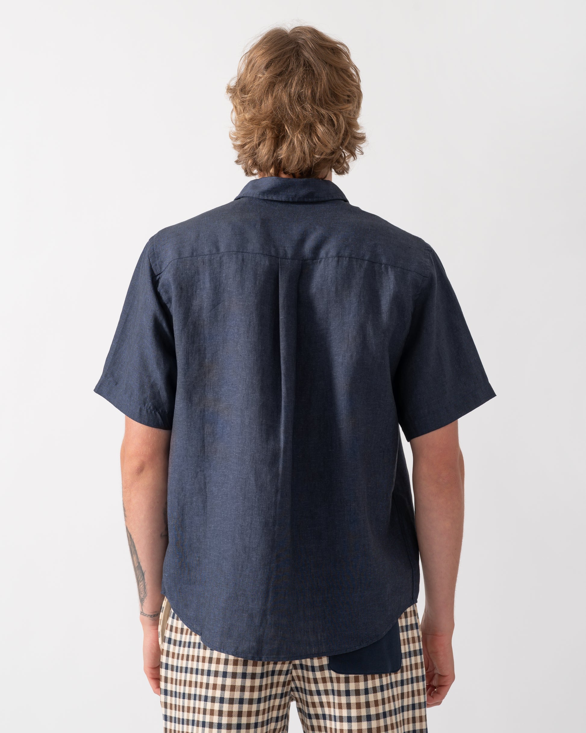 back shot of a model wearing a Colorful Standard Mens Short Sleeve Linen Shirt in Navy Blue