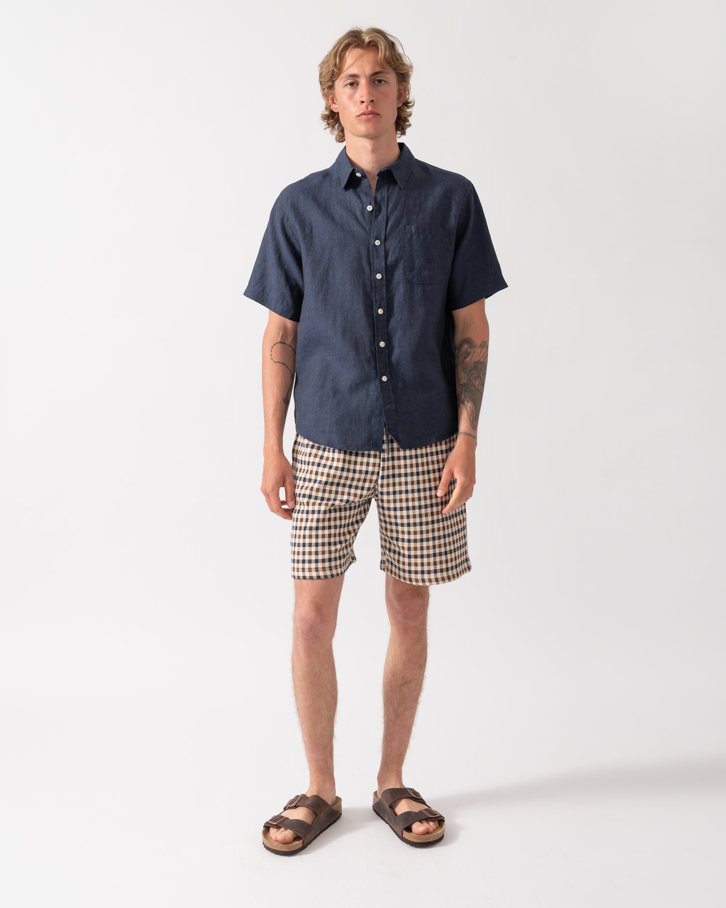 full length shot of a model wearing a Colorful Standard Mens Short Sleeve Linen Shirt in Navy Blue