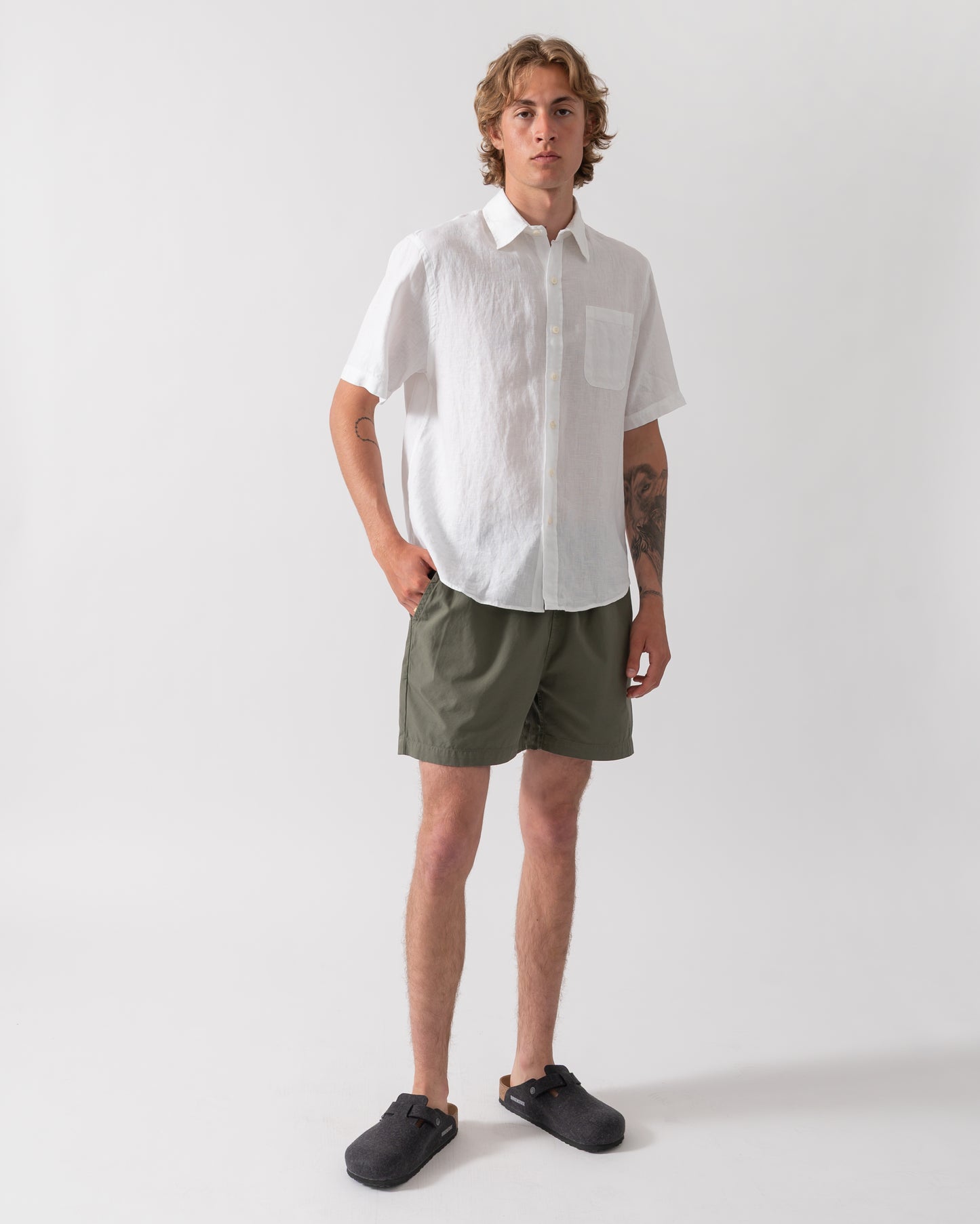 full length shot of a model wearing a Colorful Standard Mens Short Sleeve Linen Shirt in Optical White
